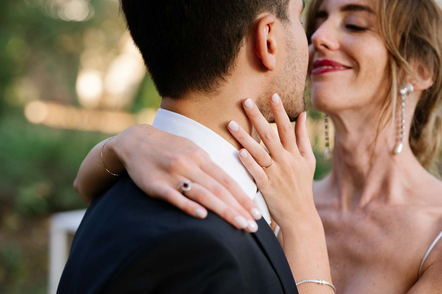 Intimate wedding moment captured as couple embraces with visible wedding rings.