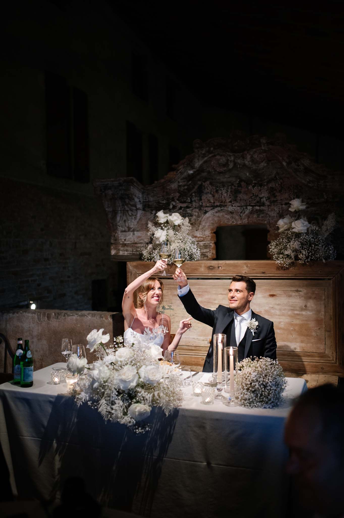 Newlyweds sharing a celebratory toast at their rustic reception table with candlelight.
