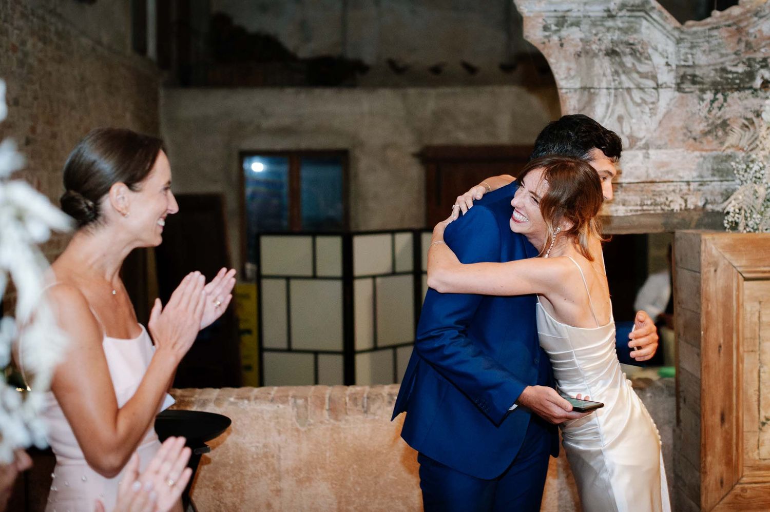 Emotional wedding ceremony moment with guests applauding in rustic venue.