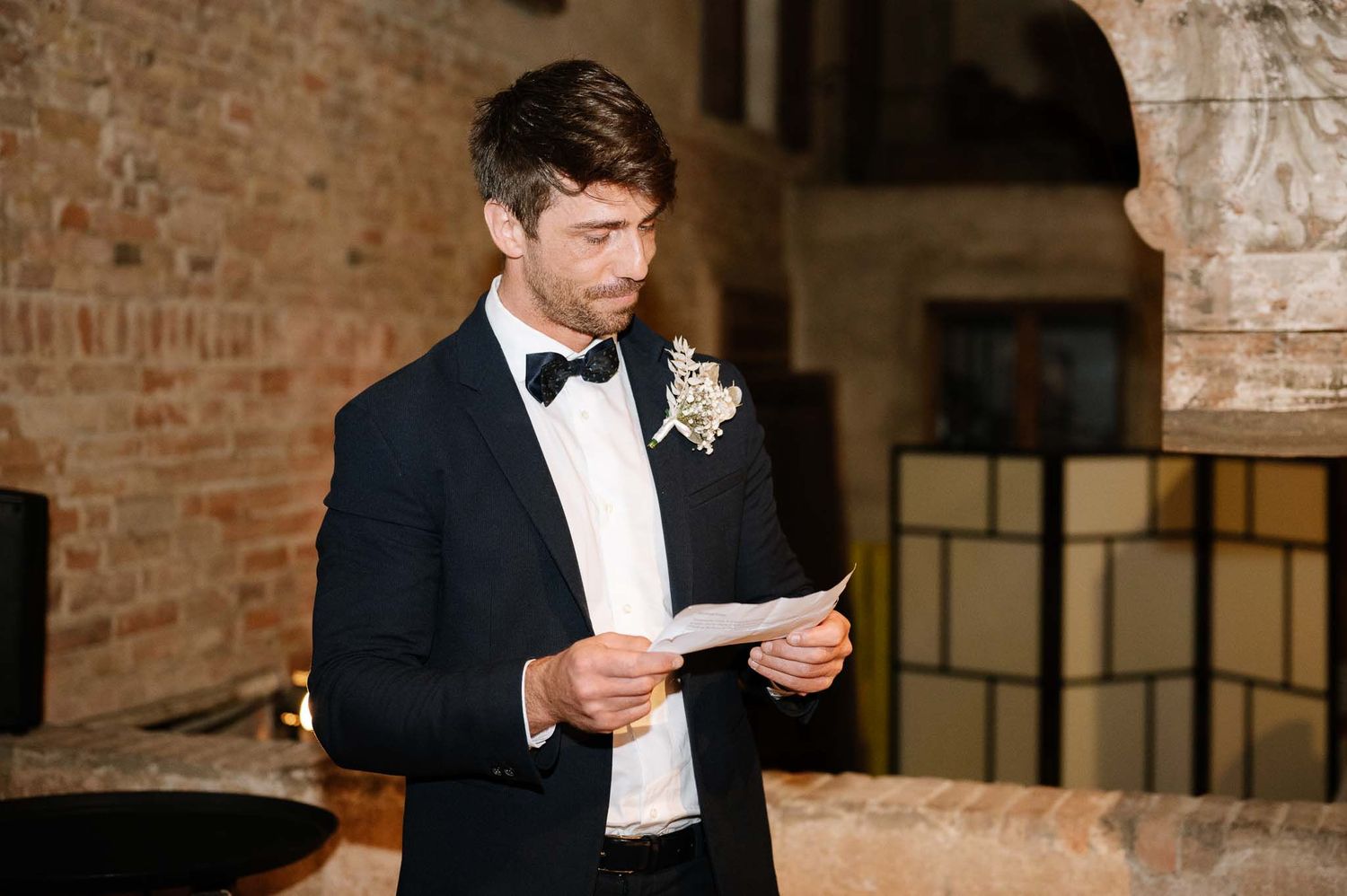 A formal wedding speech moment in a rustic brick venue with elegant lighting.