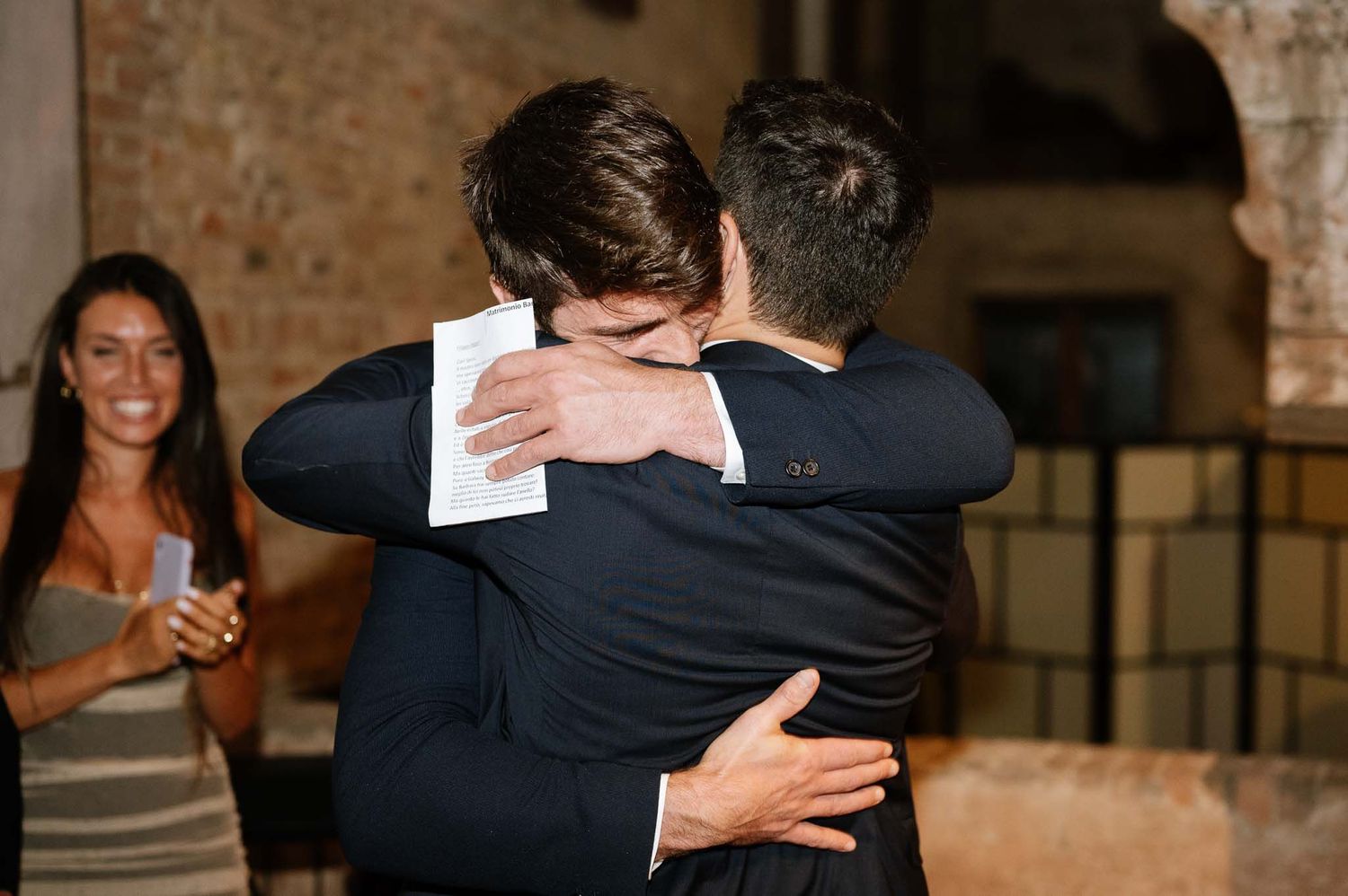 An emotional embrace during a wedding reception in a rustic venue.