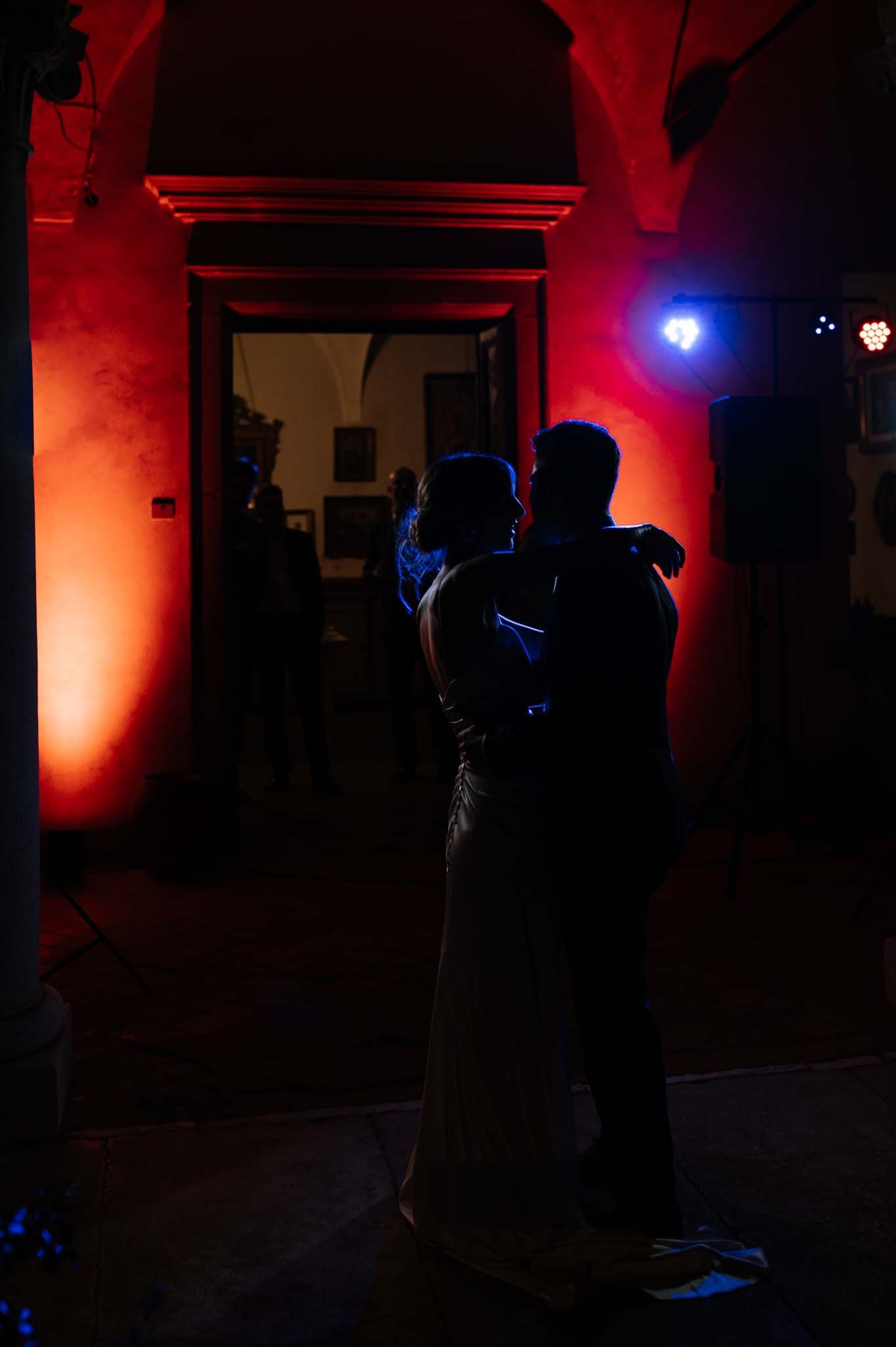 Silhouettes of dancers against dramatic red lighting create a romantic atmosphere.