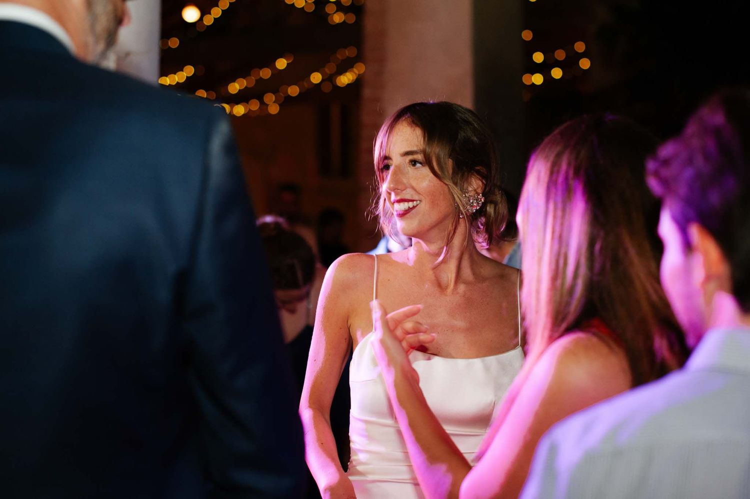 Wedding celebration with guests dancing and laughing under ambient lighting.