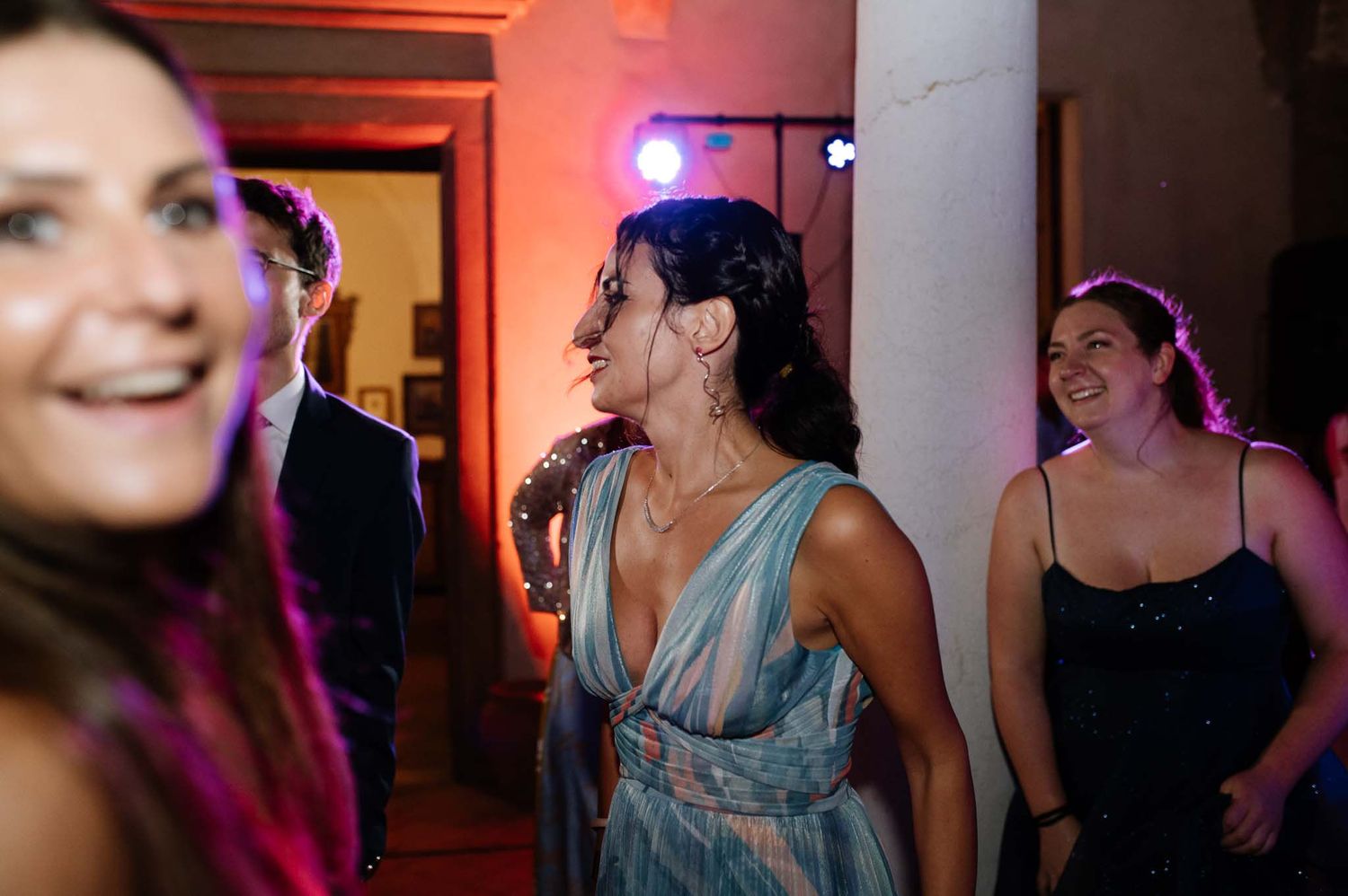 Wedding reception guests enjoying themselves on the dance floor with colorful lighting.