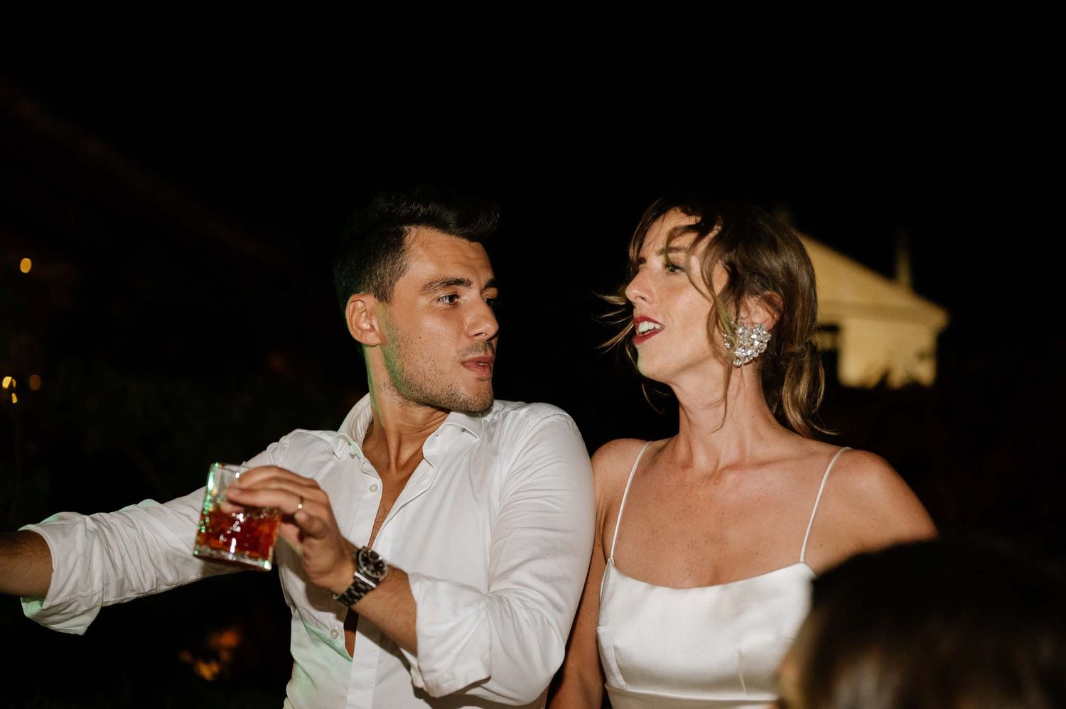 A couple enjoys drinks together at an evening celebration.