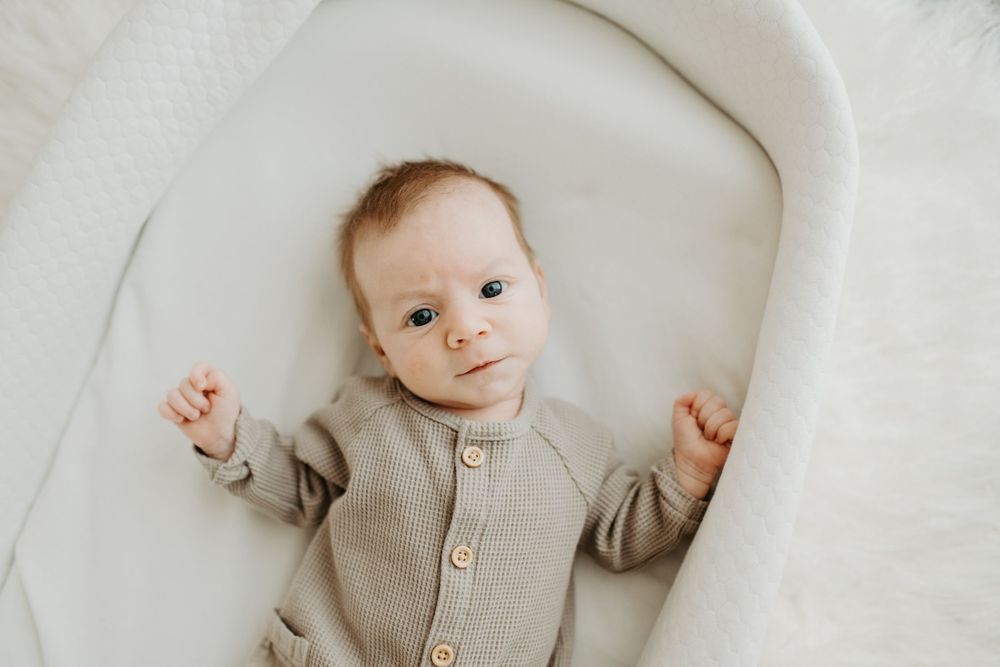 A newborn baby looks up at the camera during their lifestyle newborn session in Colorado