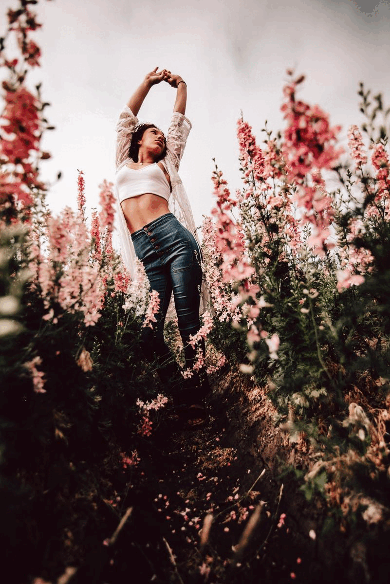 Figure stretching among pink blossoming flowers in dreamy outdoor garden scene.