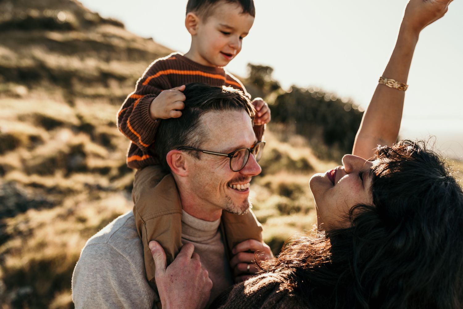 Candid family portrait filled with laughter and joy during golden hour in mountain setting.