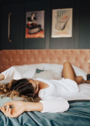 Intimate bedroom photography with soft white bedding and teal accents in a romantic setting.