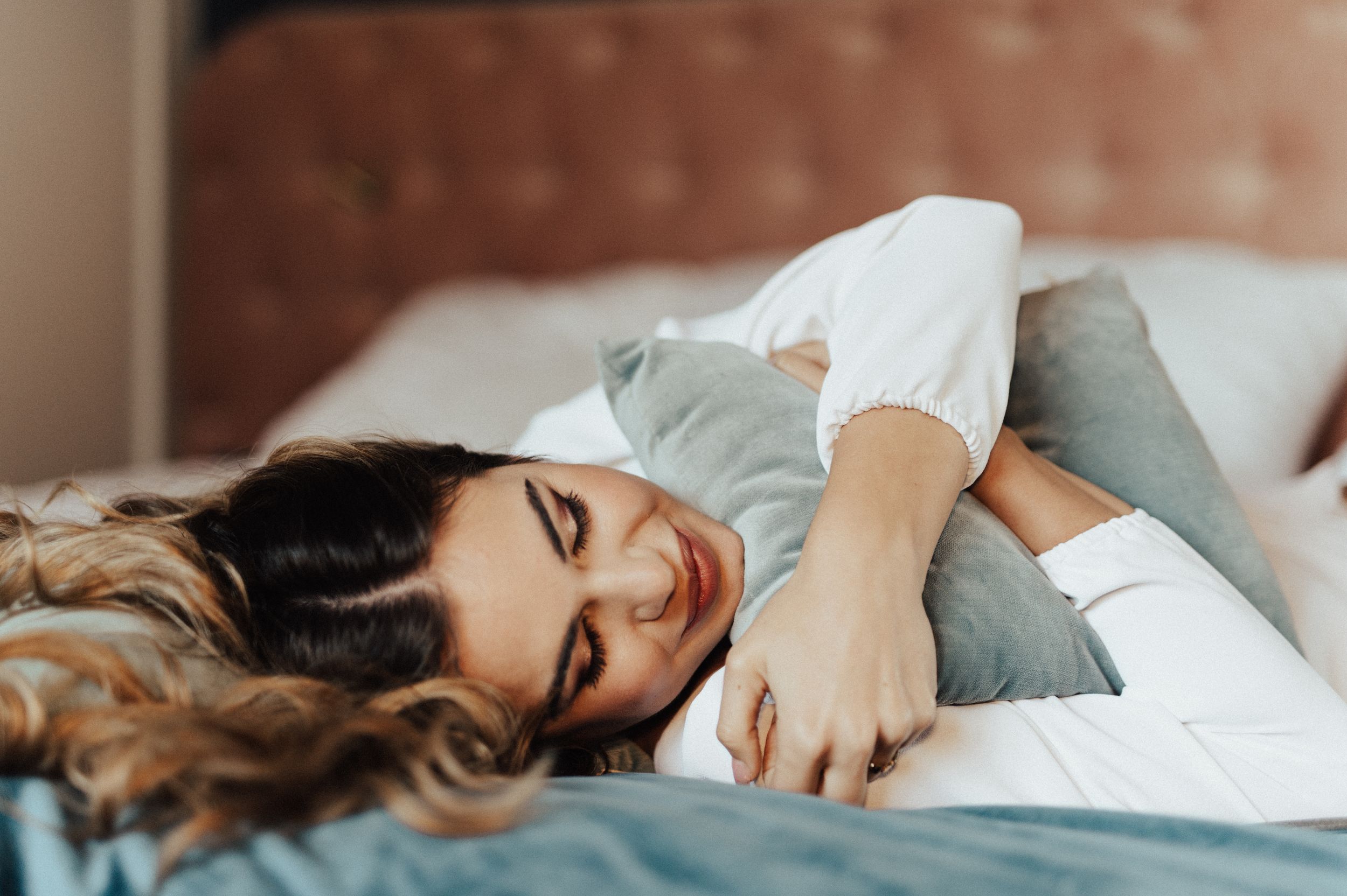Artistic boudoir photos showing intimate poses on a bed with tufted headboard.