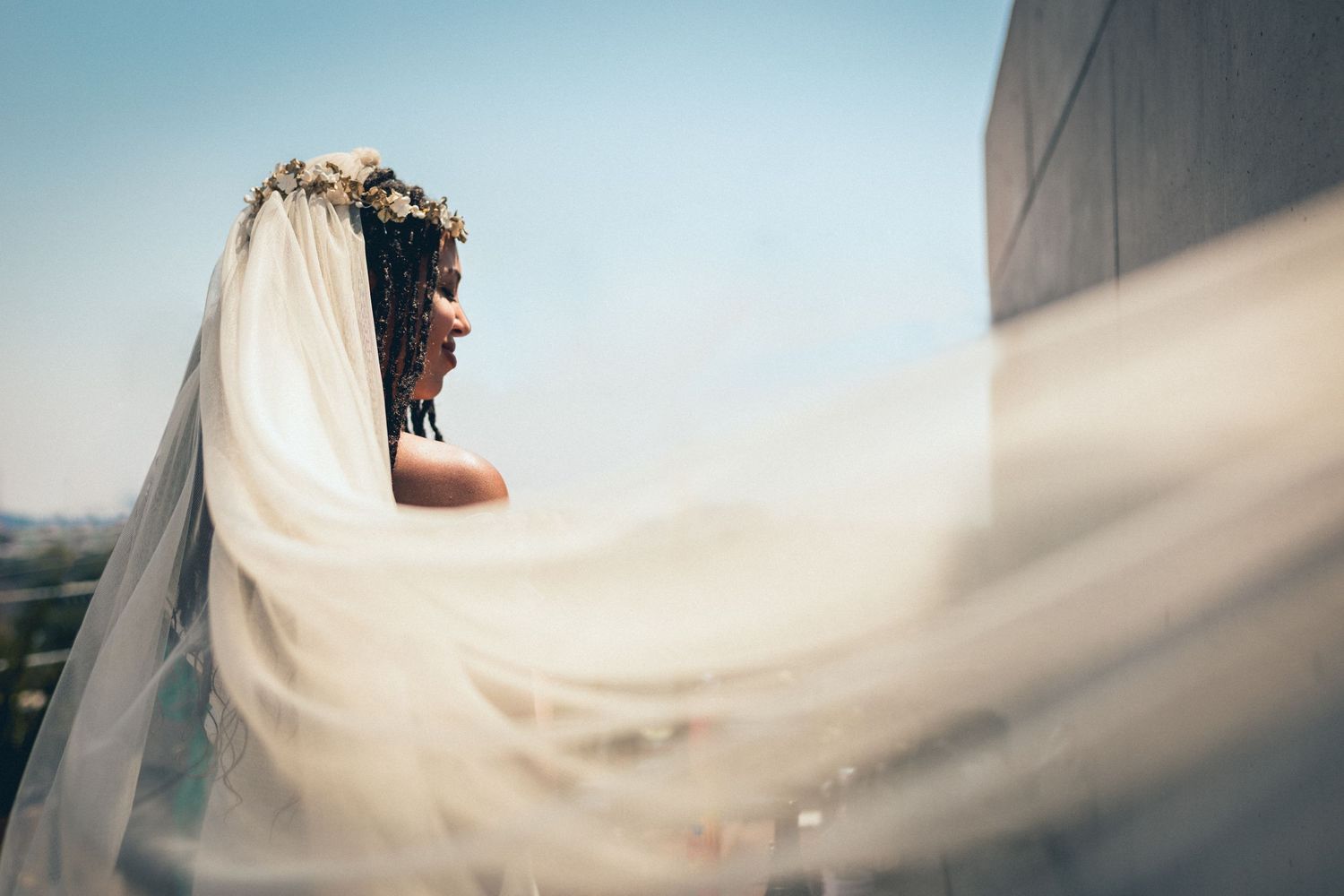 Flowing white wedding dress fabric billows gracefully in the breeze against blue sky.