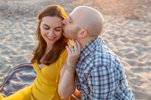 A couple shares a romantic moment on the beach at sunset.