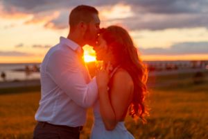 A silhouetted couple shares an intimate moment during a vibrant sunset.