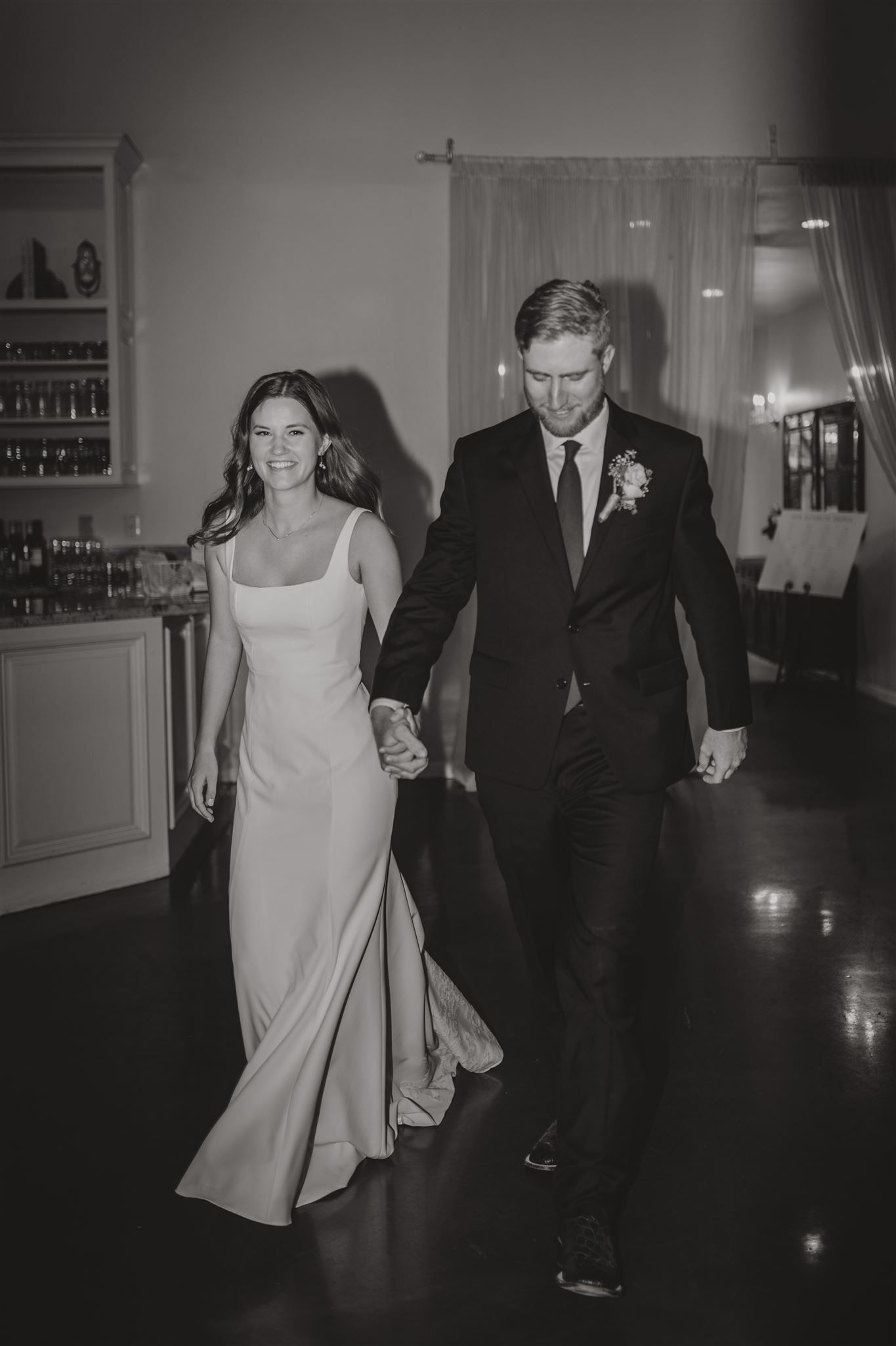 Black and white photo of couple walking together in formal attire.