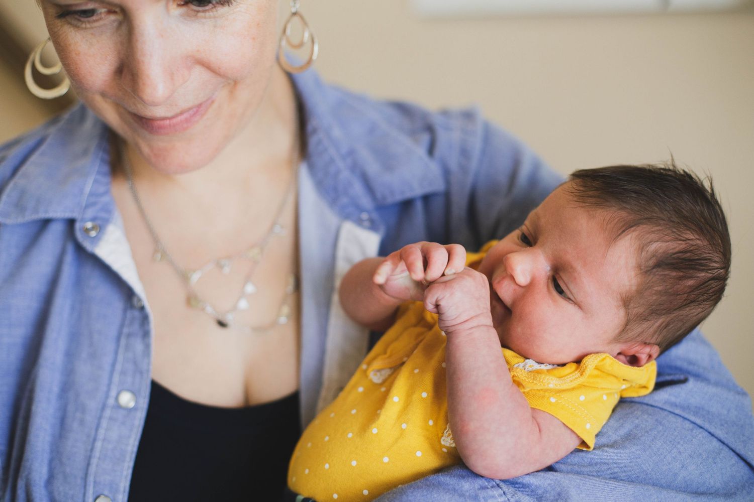 Everett newborn photographer: a mother hold her newborn baby daughter at an in-home newborn session