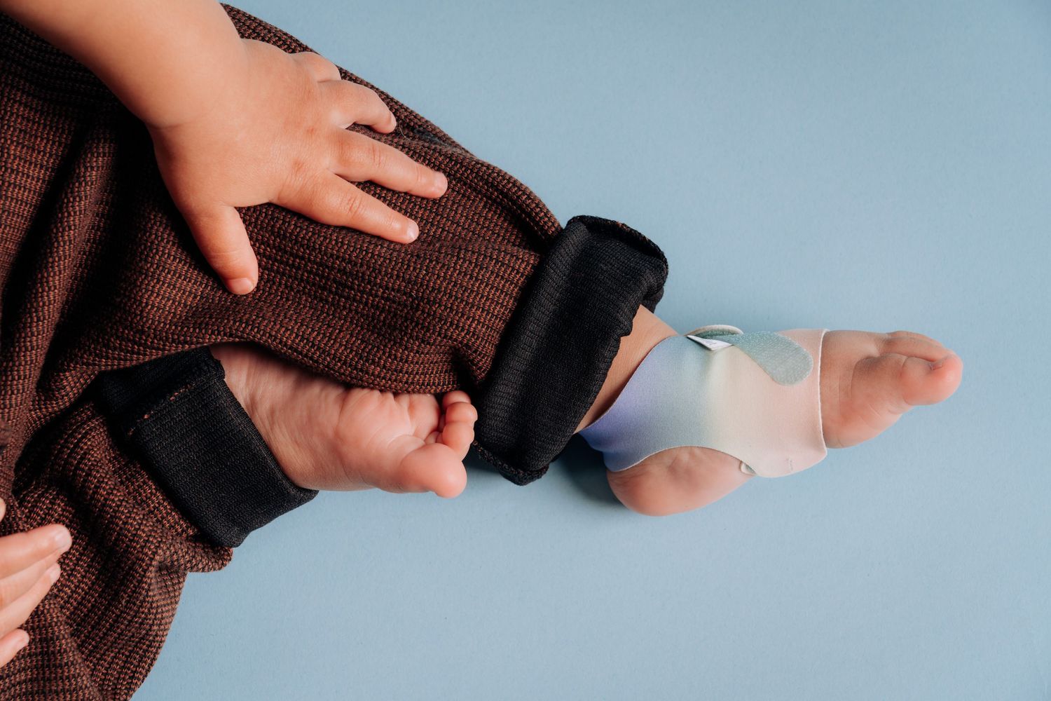 Close-up of hands adjusting therapeutic foot device on infant.