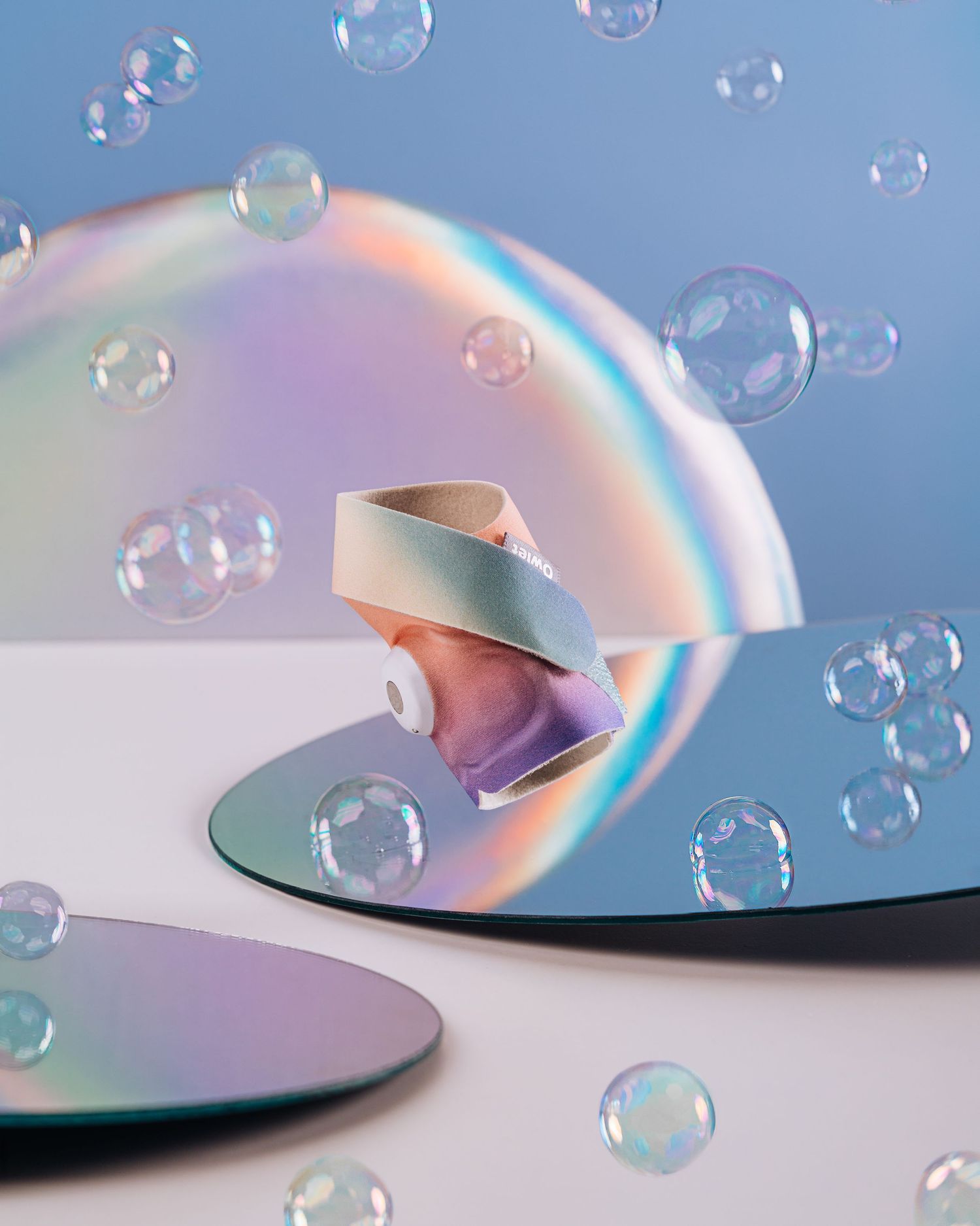 Artistic composition with soap bubbles and iridescent rainbow reflections against a blue background.