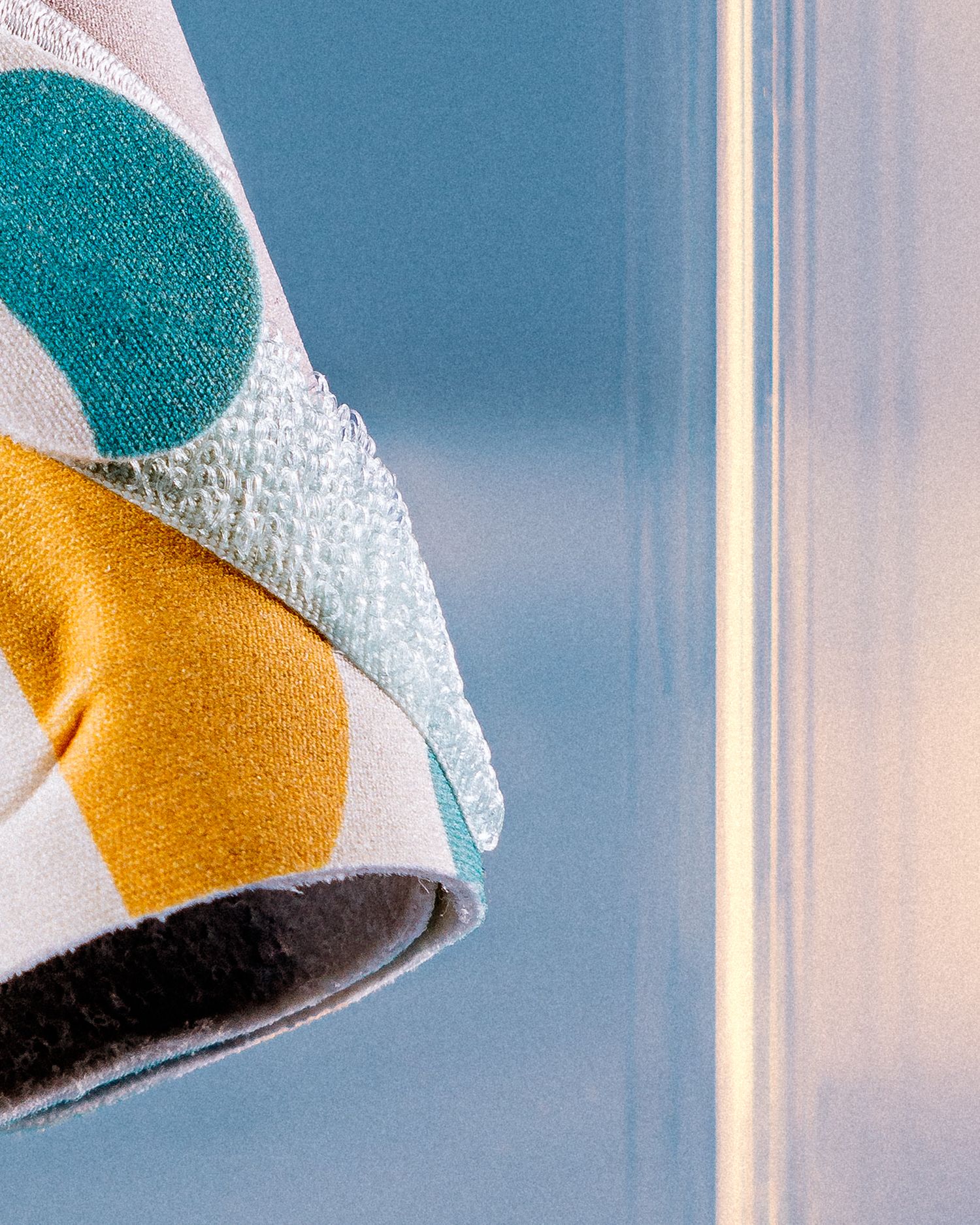 Textured fabric detail showing geometric patterns in teal yellow and white against blue background.