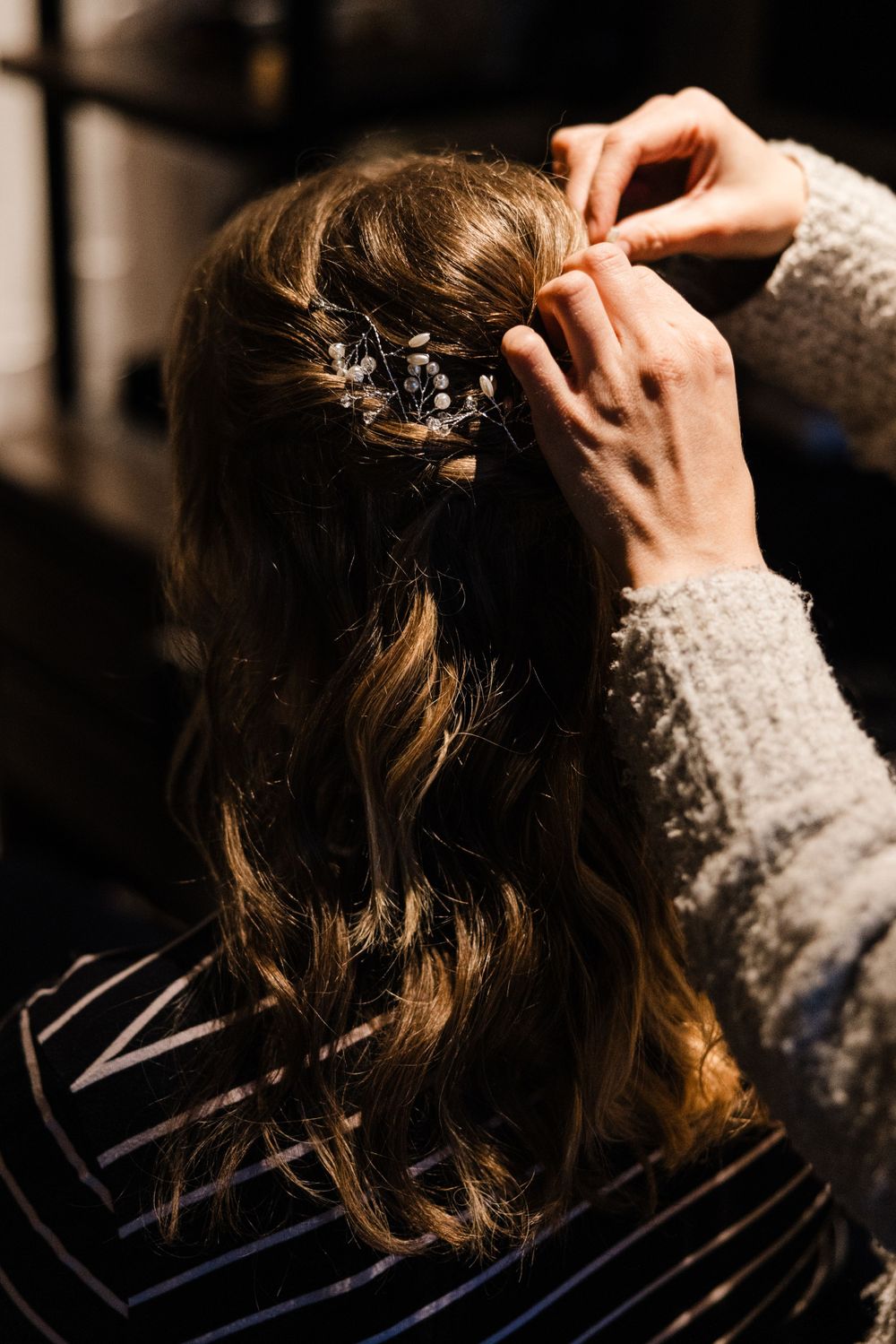Close-up shot of hands styling an elegant braided hairstyle with decorative pins for a special occasion.