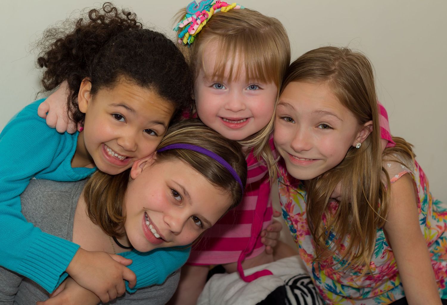 Four children pose together for a fun group photo with bright smiles.