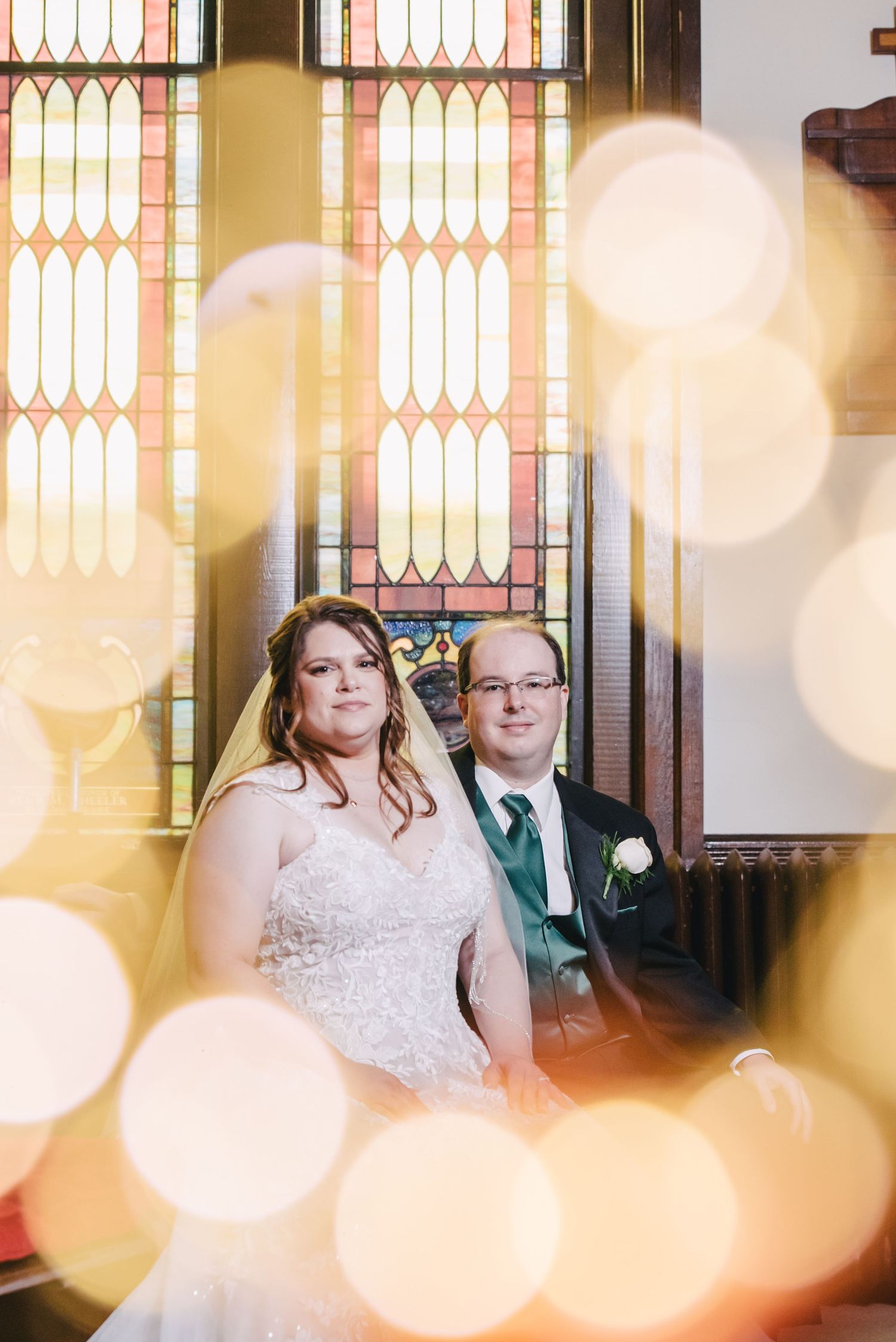 A romantic portrait of a couple against stained glass windows with dreamy bokeh light effects.
