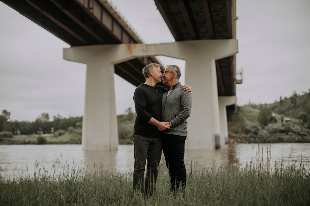 Couple sharing an intimate moment under a concrete bridge structure.