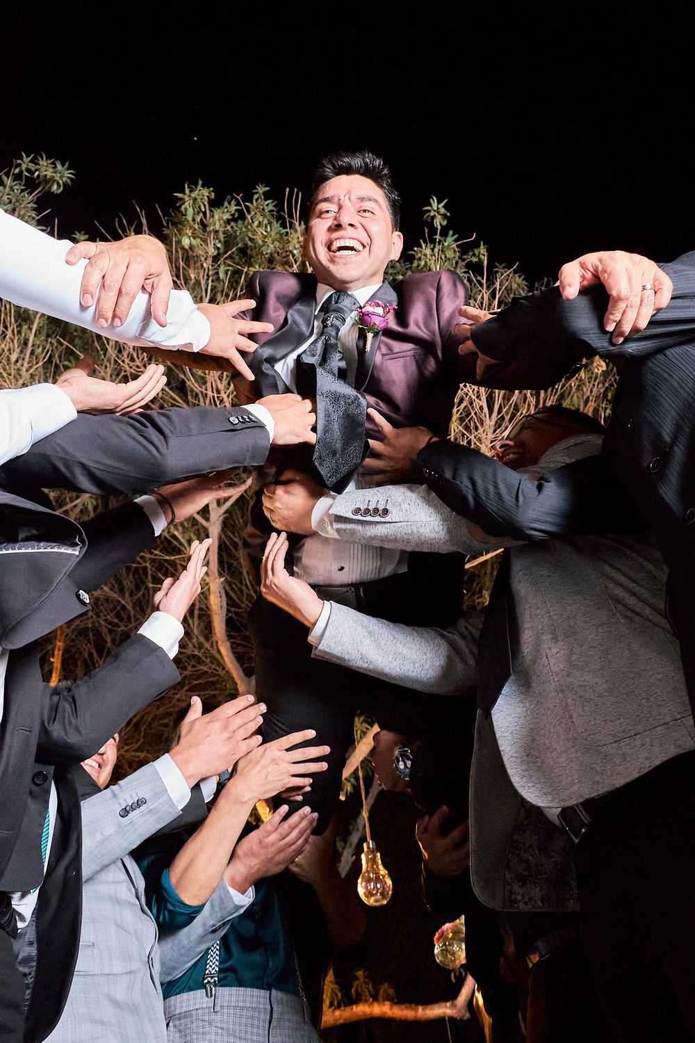 Groomsmen lift and celebrate with the groom during wedding festivities.