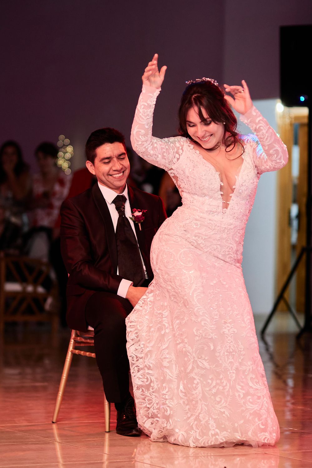 Couple dances together on wooden dance floor during wedding celebration.