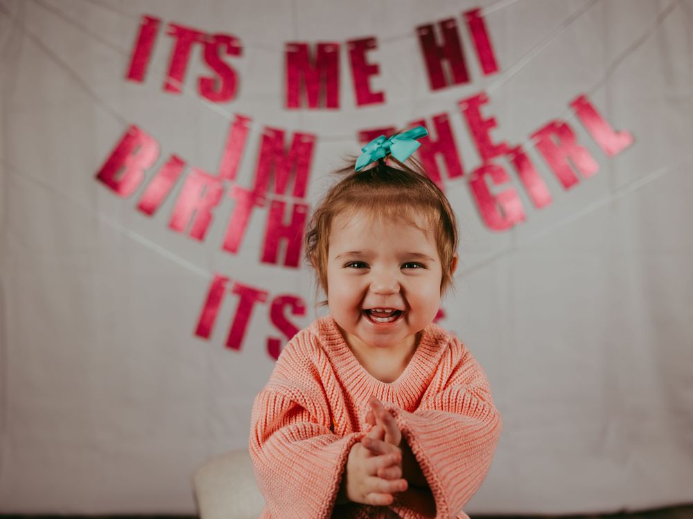 Birthday celebration with pink lettering banner backdrop and joyful expression.