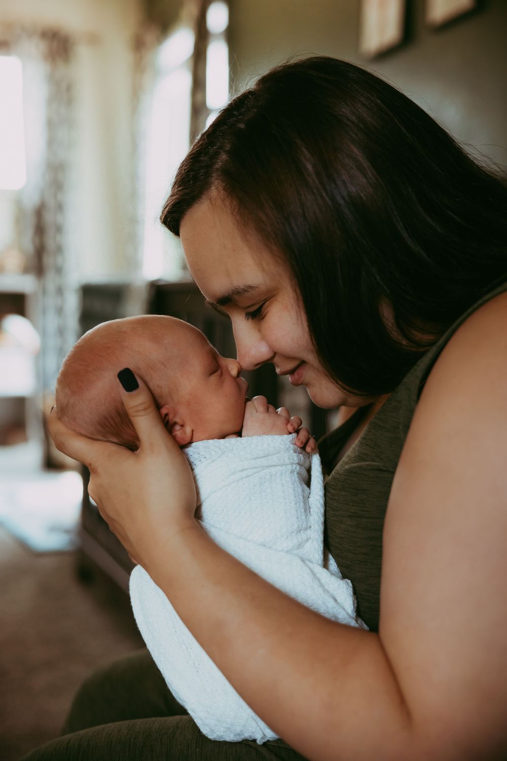 An intimate moment shared between parent and newborn in soft natural lighting.