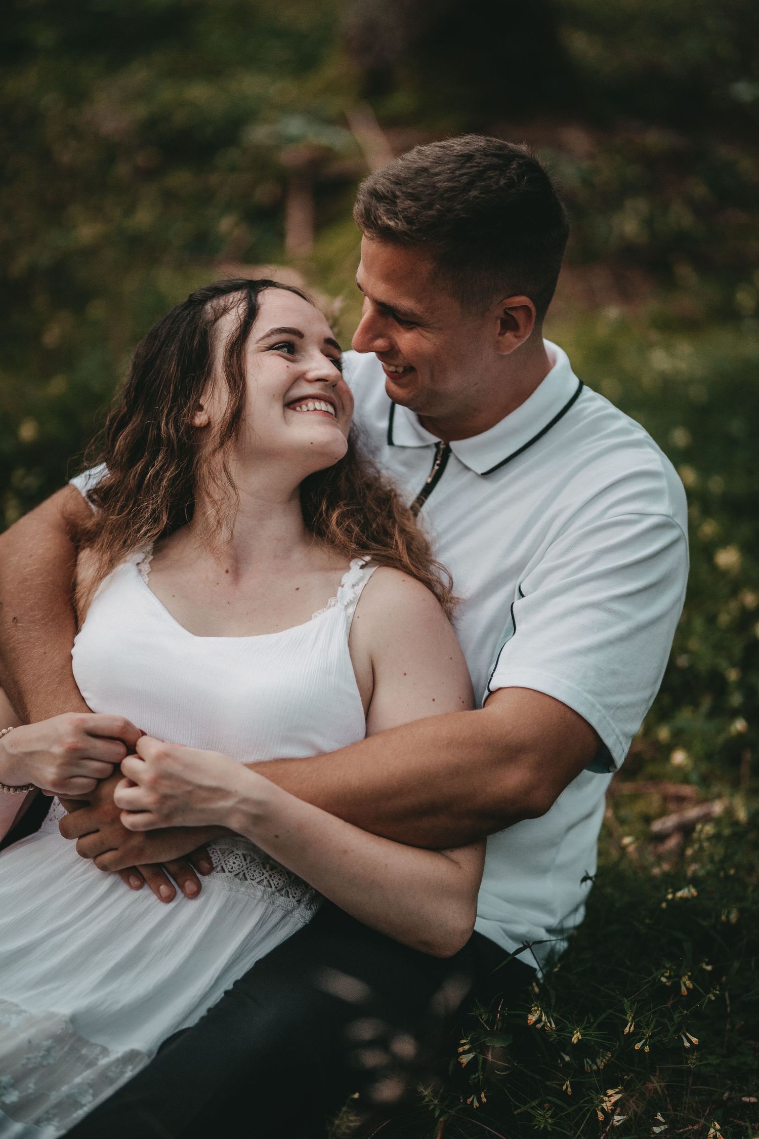 Intimate couple's photoshoot with natural poses in a garden setting.