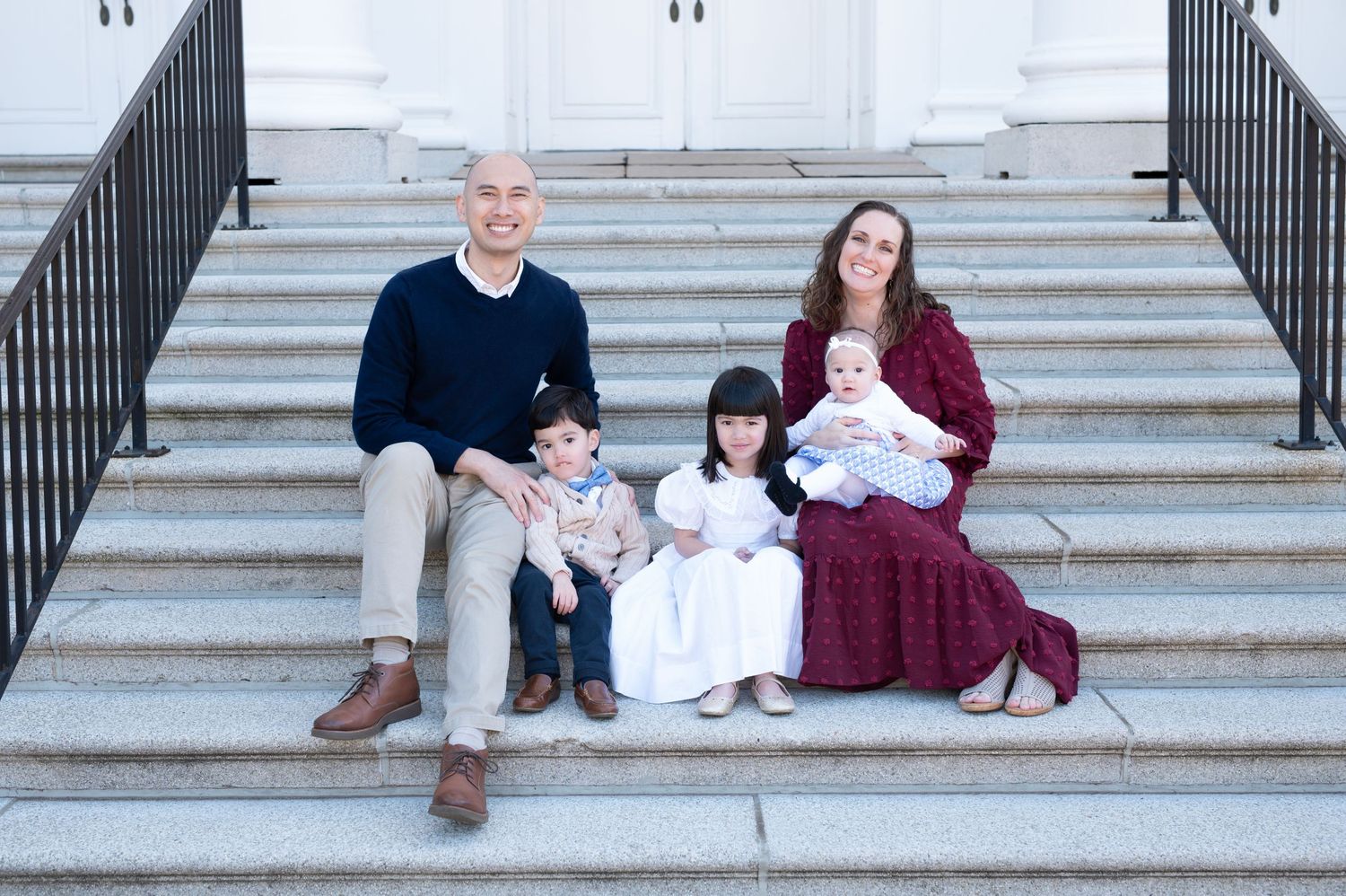 Group of people sitting casually on wide stone steps outdoors.