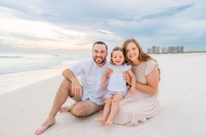Family sitting together on pristine white sand beach at sunset.