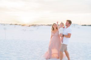 Family enjoying a sunset moment together on white sand beach dunes.