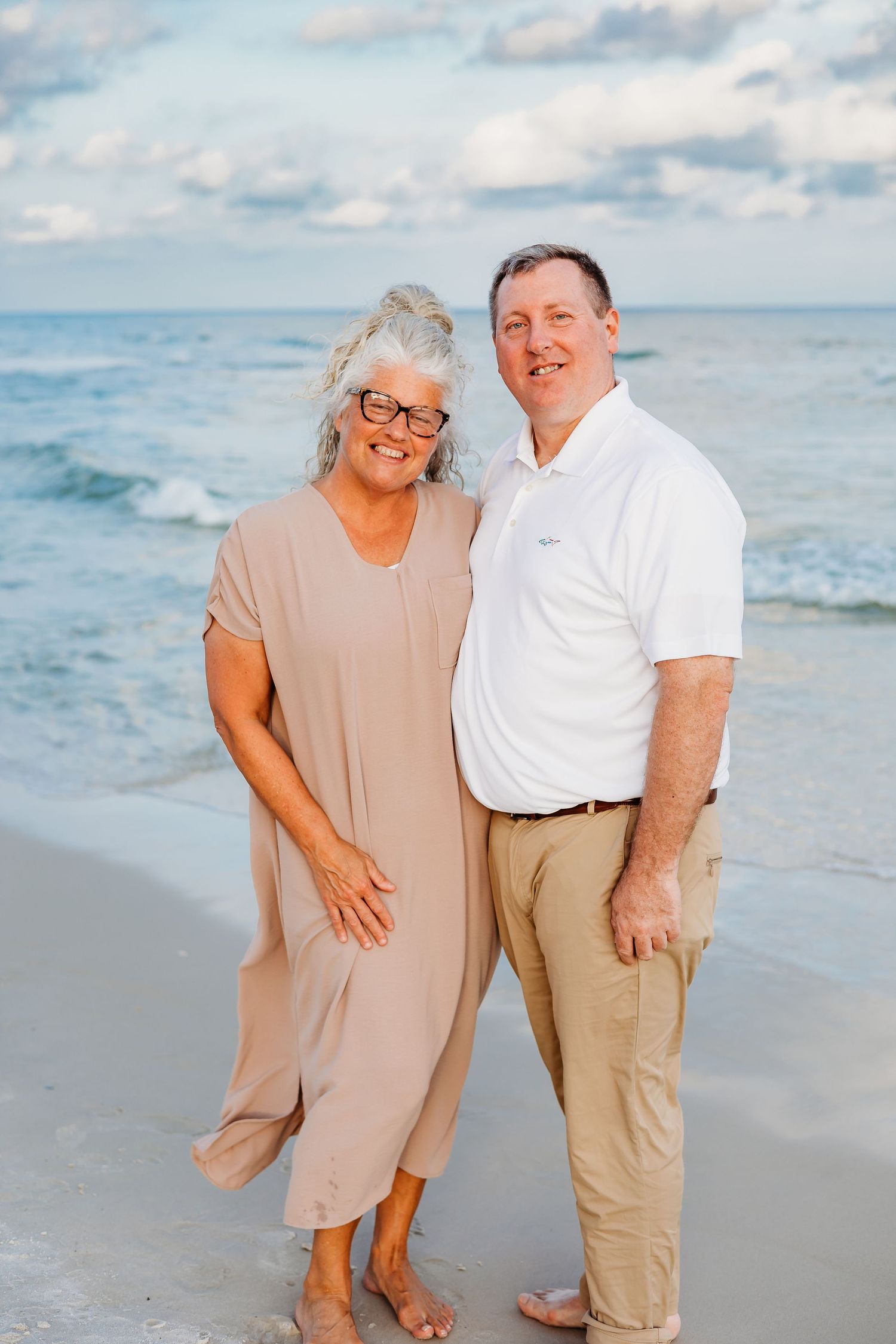 Couple in casual beachwear sharing romantic moments along the ocean shoreline.