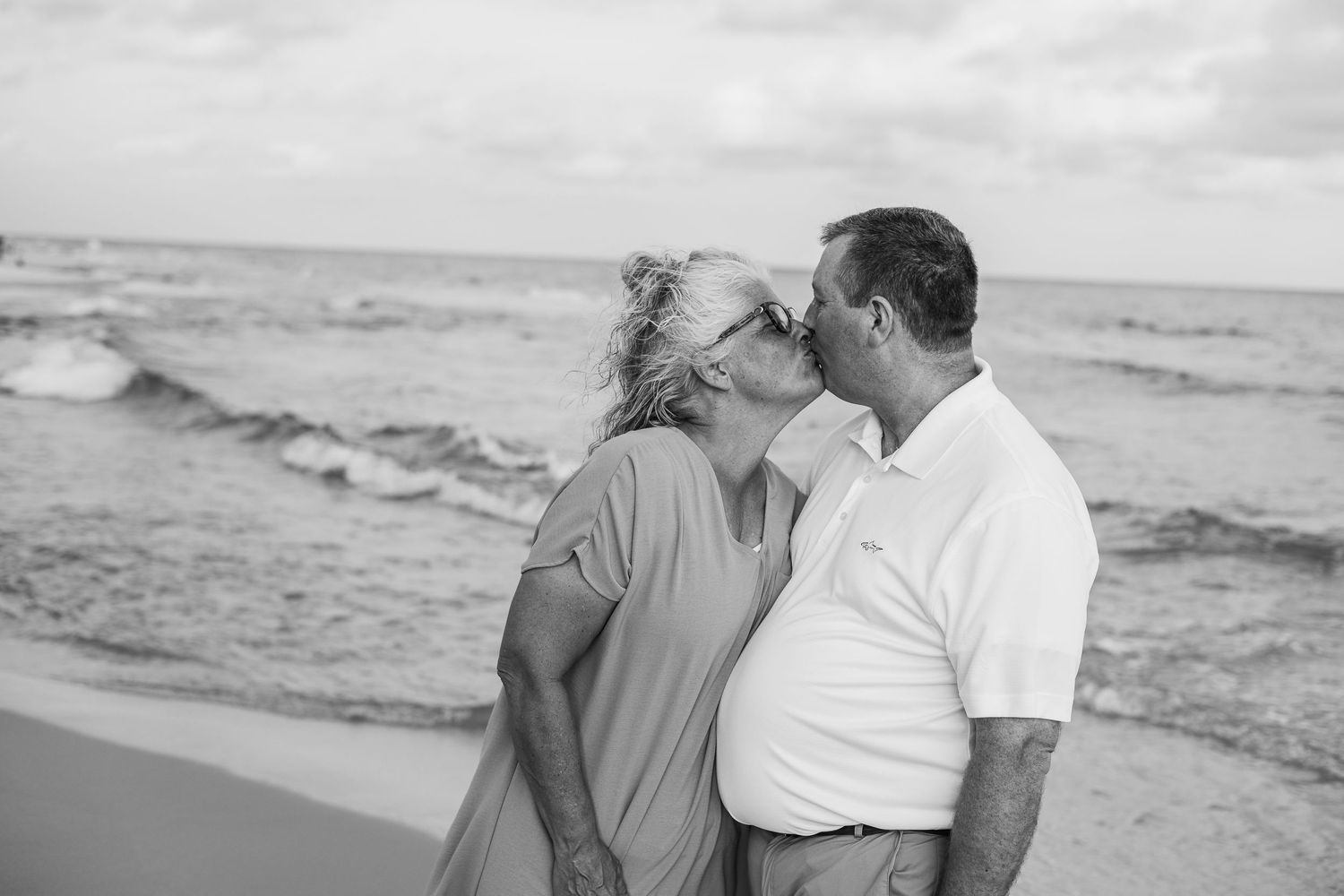 Intimate black and white beach portrait with waves crashing in background.