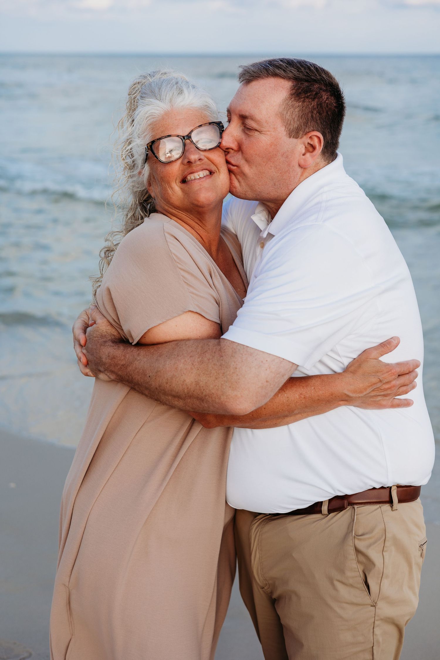 Sweet embraces shared during sunset beach photoshoot with ocean waves in background.