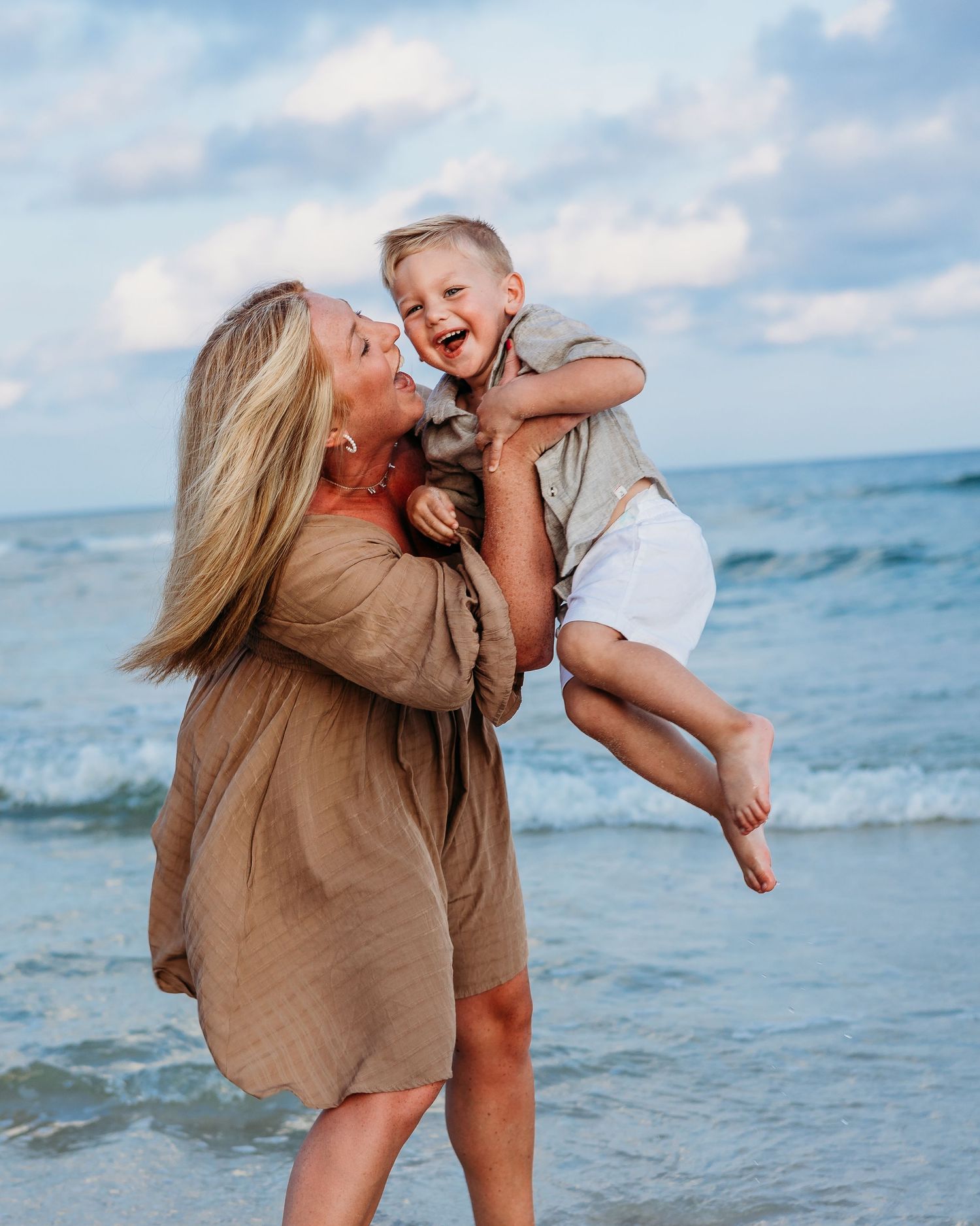 Joyful interaction captured during beachside photoshoot with waves in background.