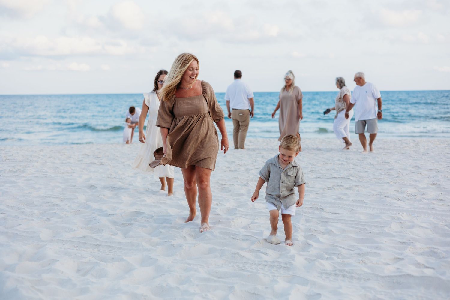 Group walking along pristine white sand beach with turquoise ocean waters in background.