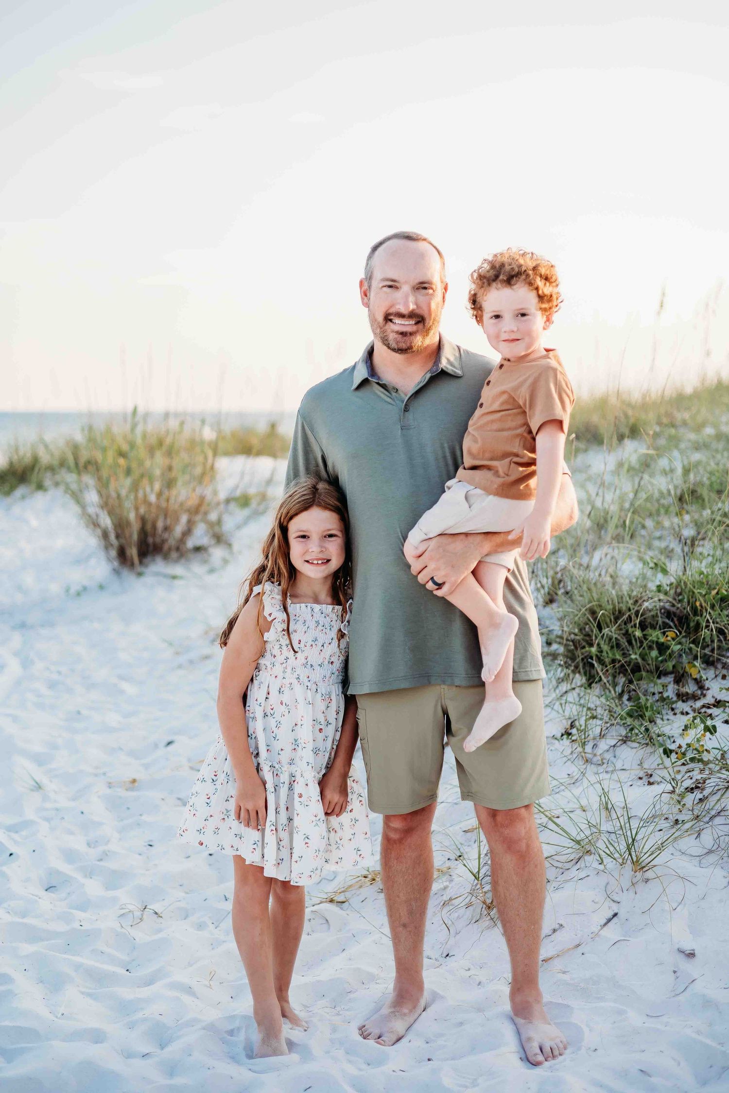 Candid family beach portraits with members wearing coordinated casual outfits.