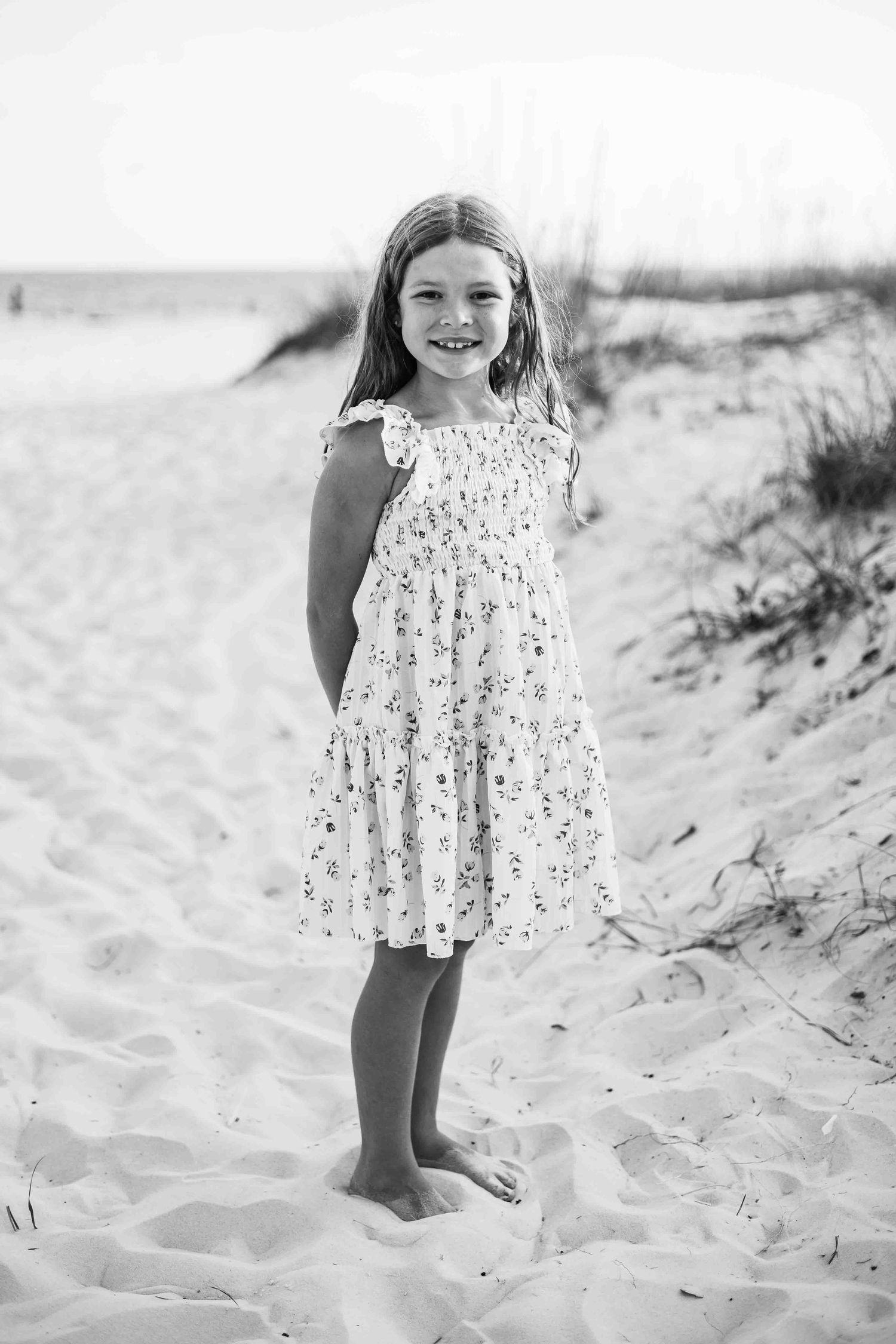 Black and white beach photography featuring a floral dress against sandy dunes.