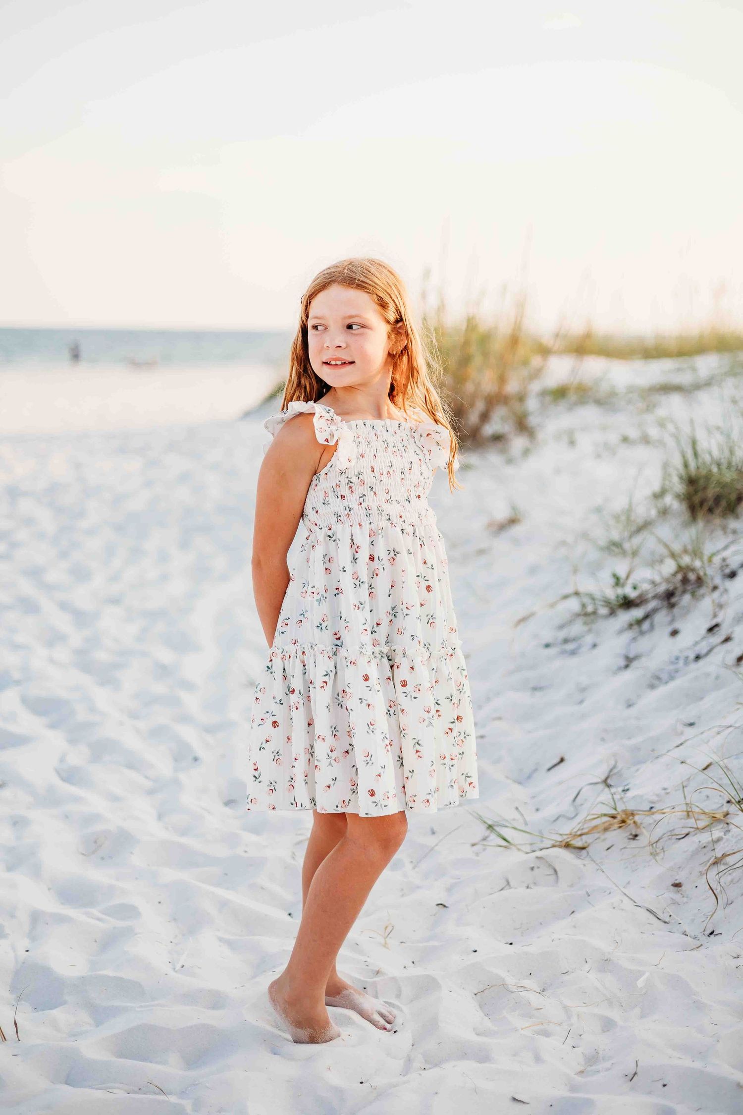 Soft lighting illuminates a beach scene with white sand dunes and coastal grass.