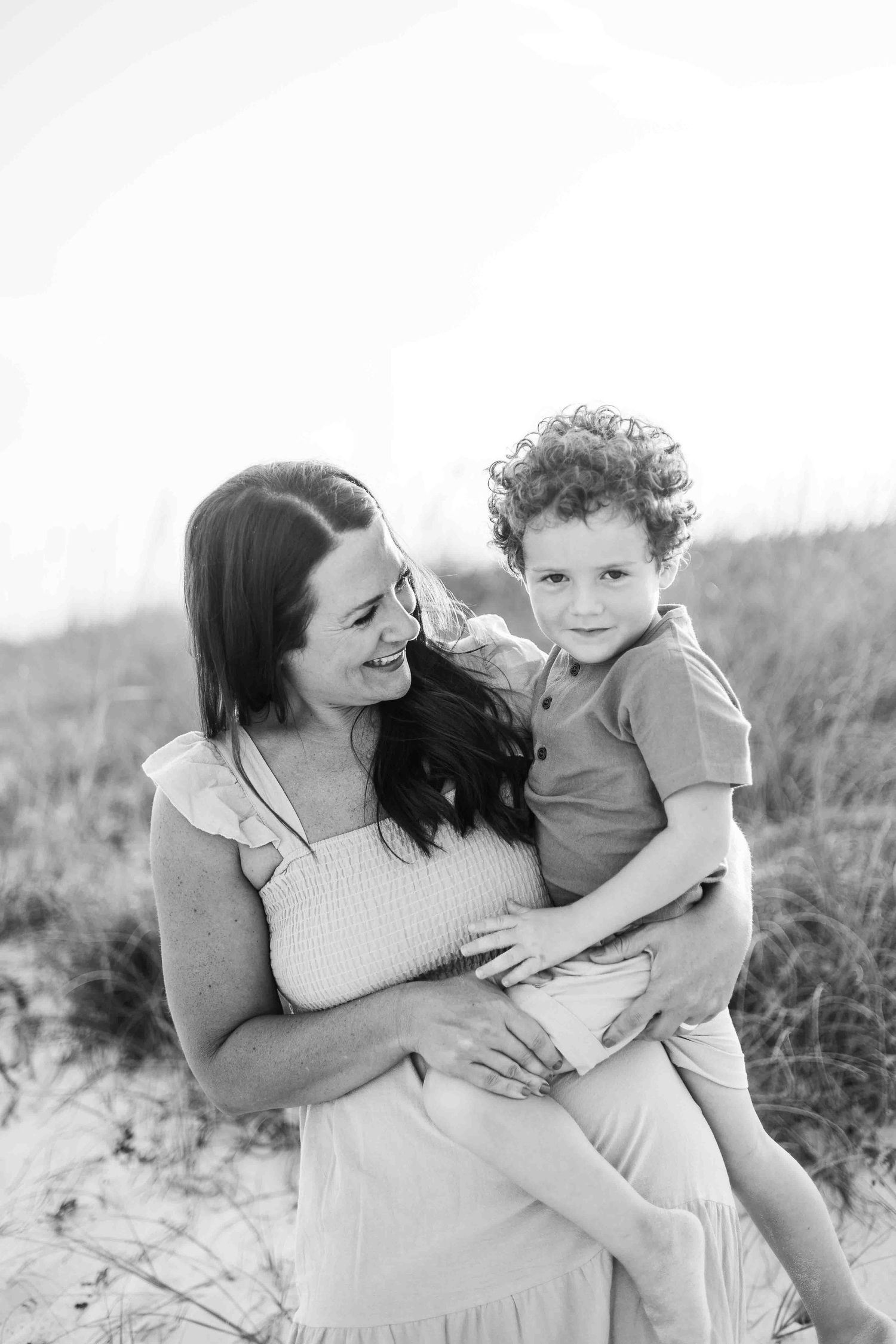 Intimate family photos taken on sandy dunes during golden hour.