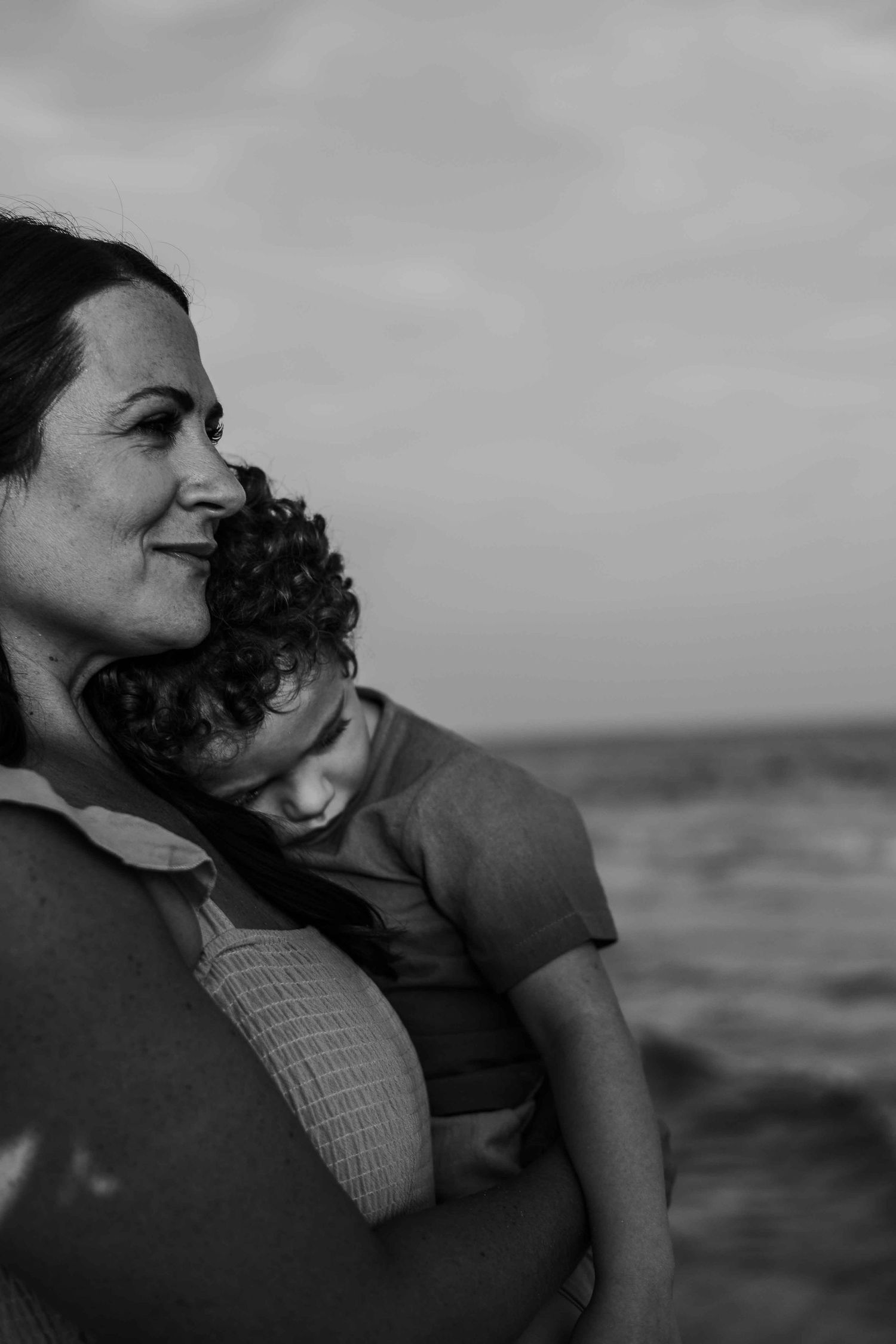 Black and white intimate portrait captured against ocean backdrop.