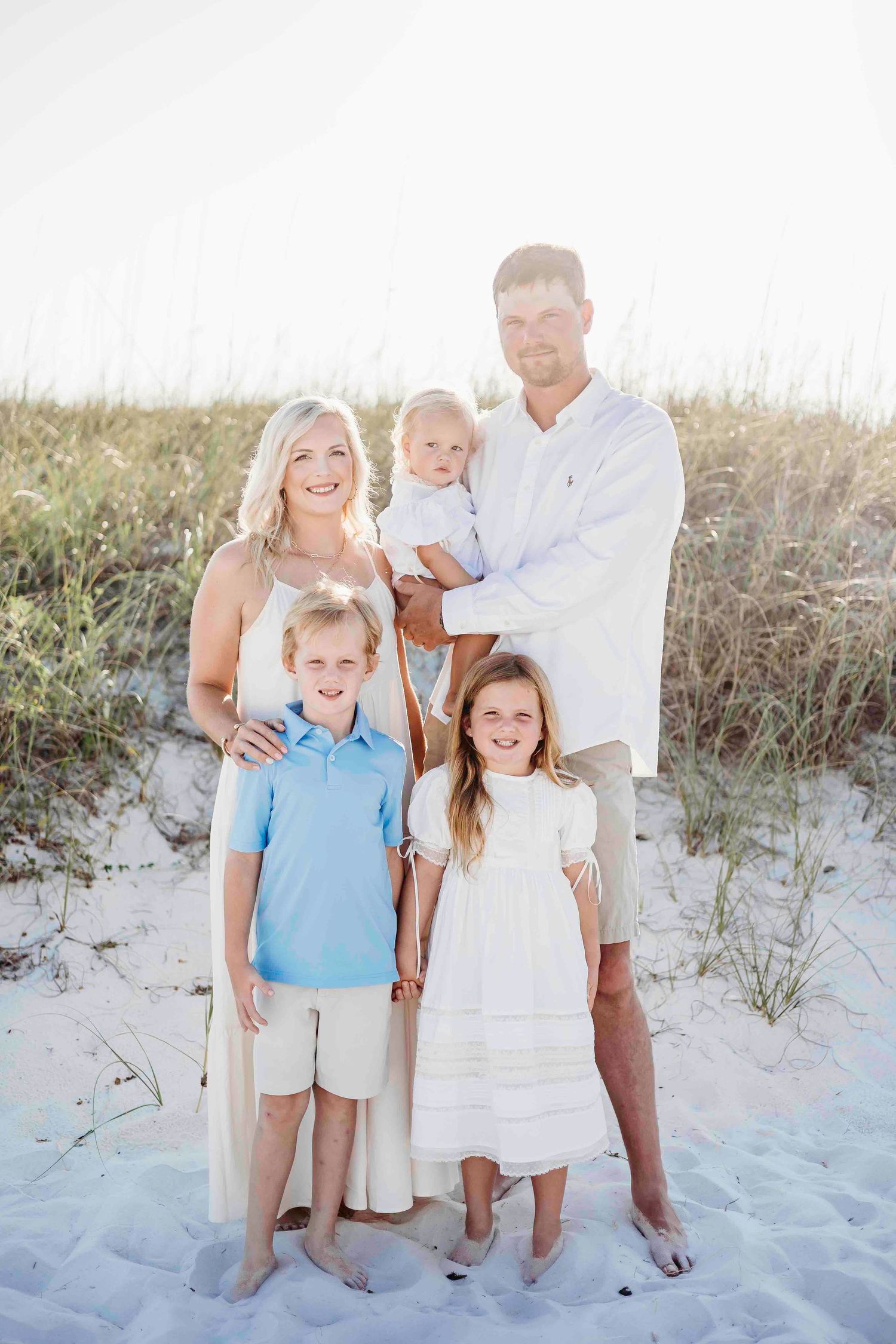 Casual beach family portrait with children and adults in coordinated summer attire.