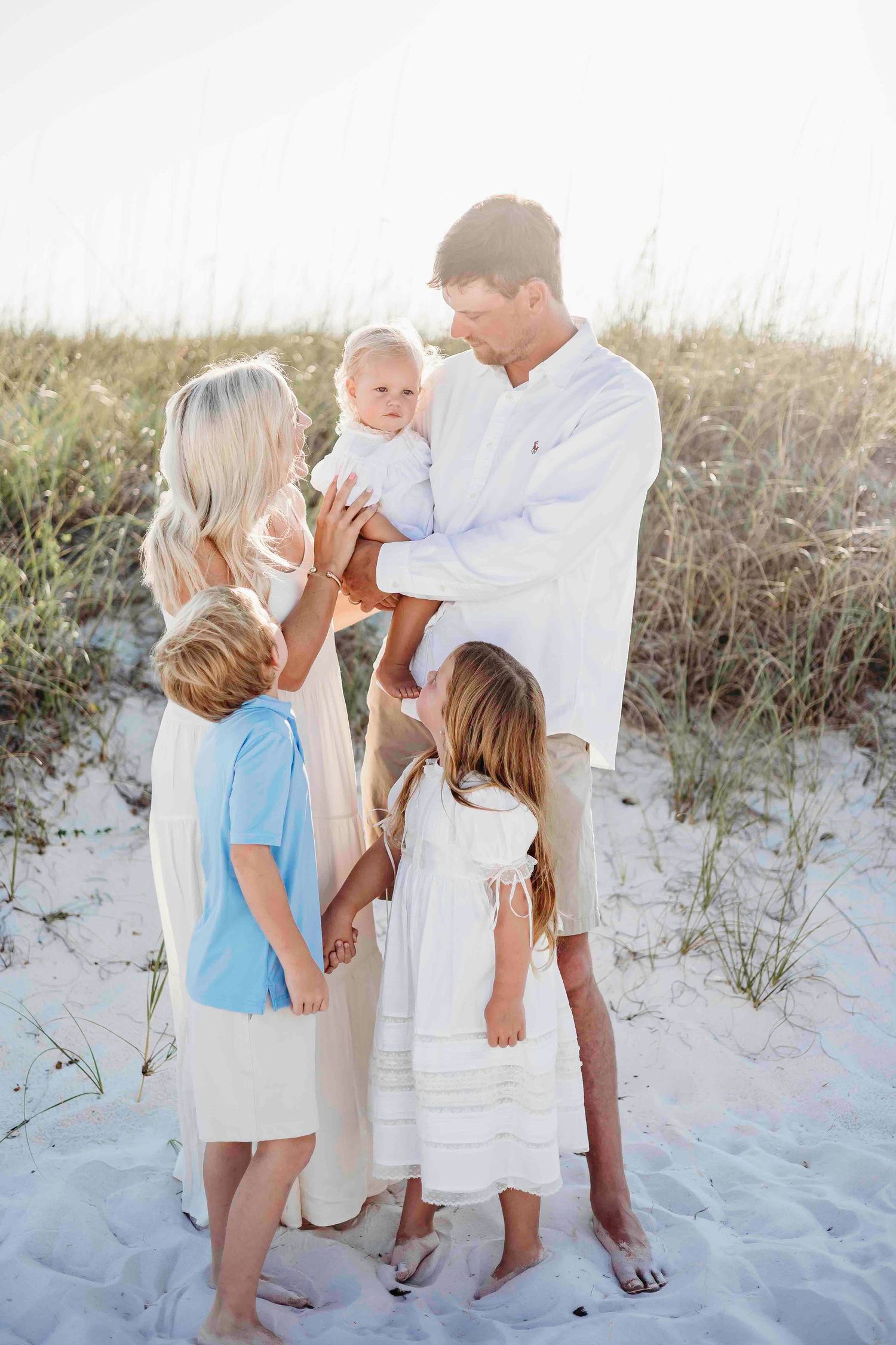 Candid family moment captured on beach with everyone in white and blue outfits.