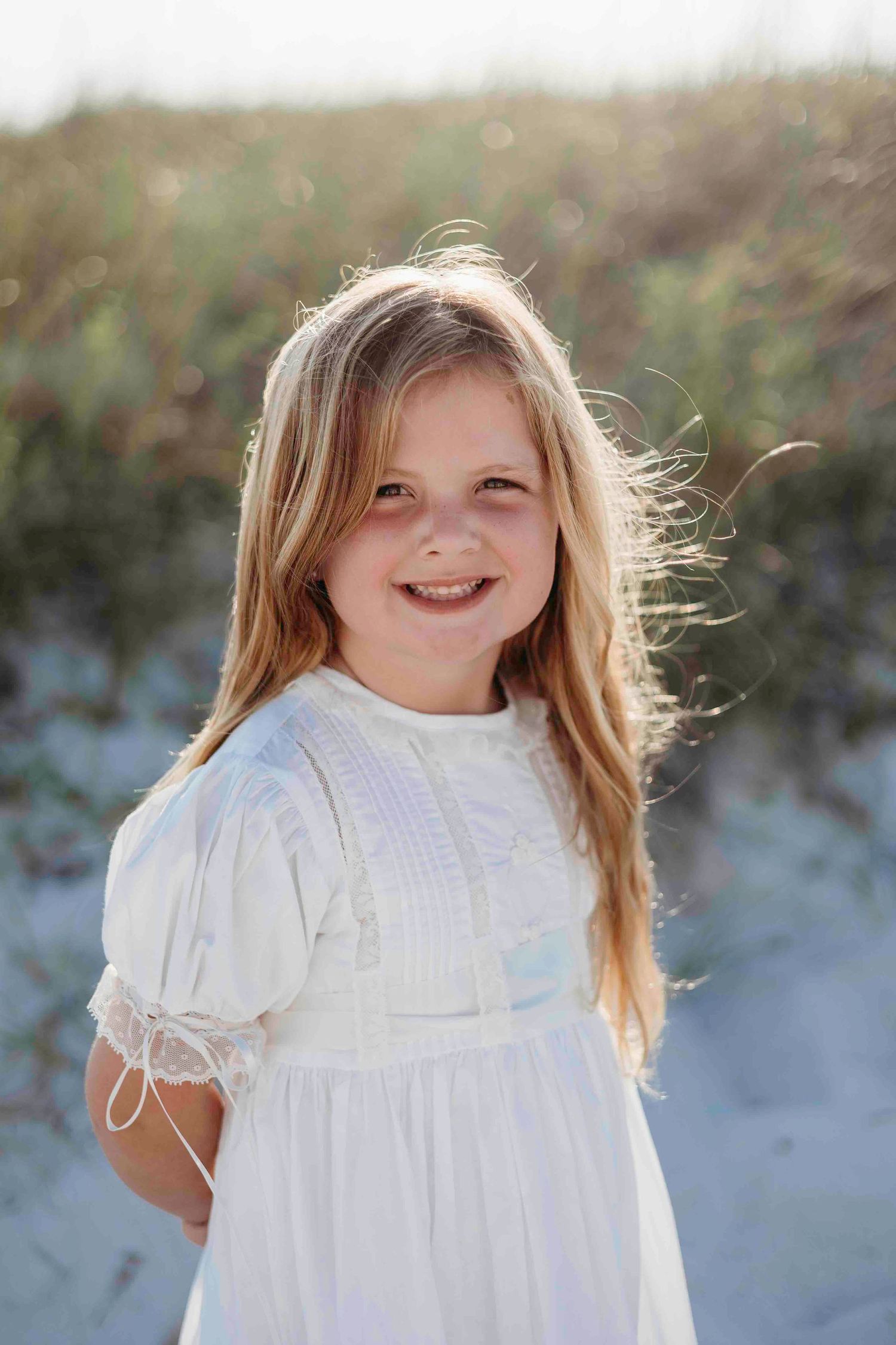 A joyful moment captured of a child in white dress at the beach.