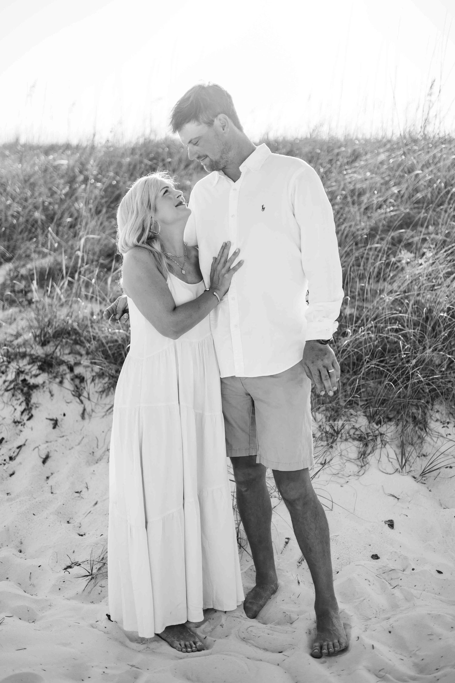 Romantic black and white photo of couple sharing intimate moment on beach.