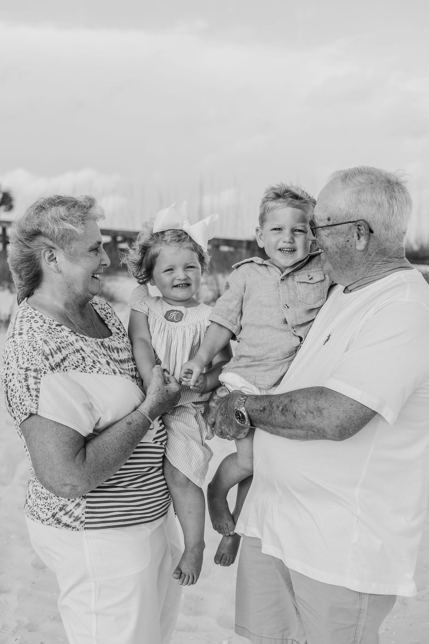 Black and white photo of family members playing and laughing on a beach.