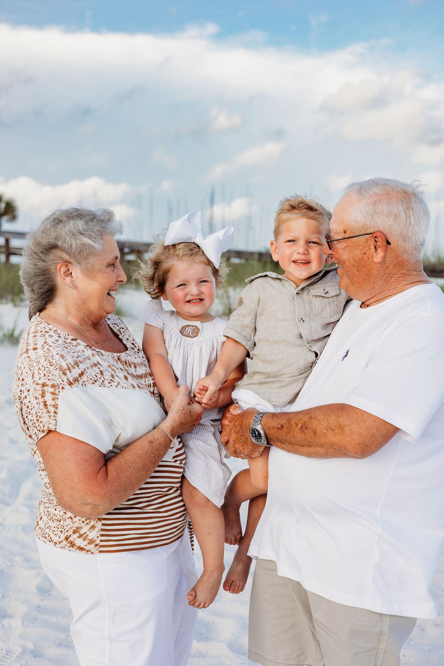 Candid family beach photos showing playful interactions against a blue sky background.